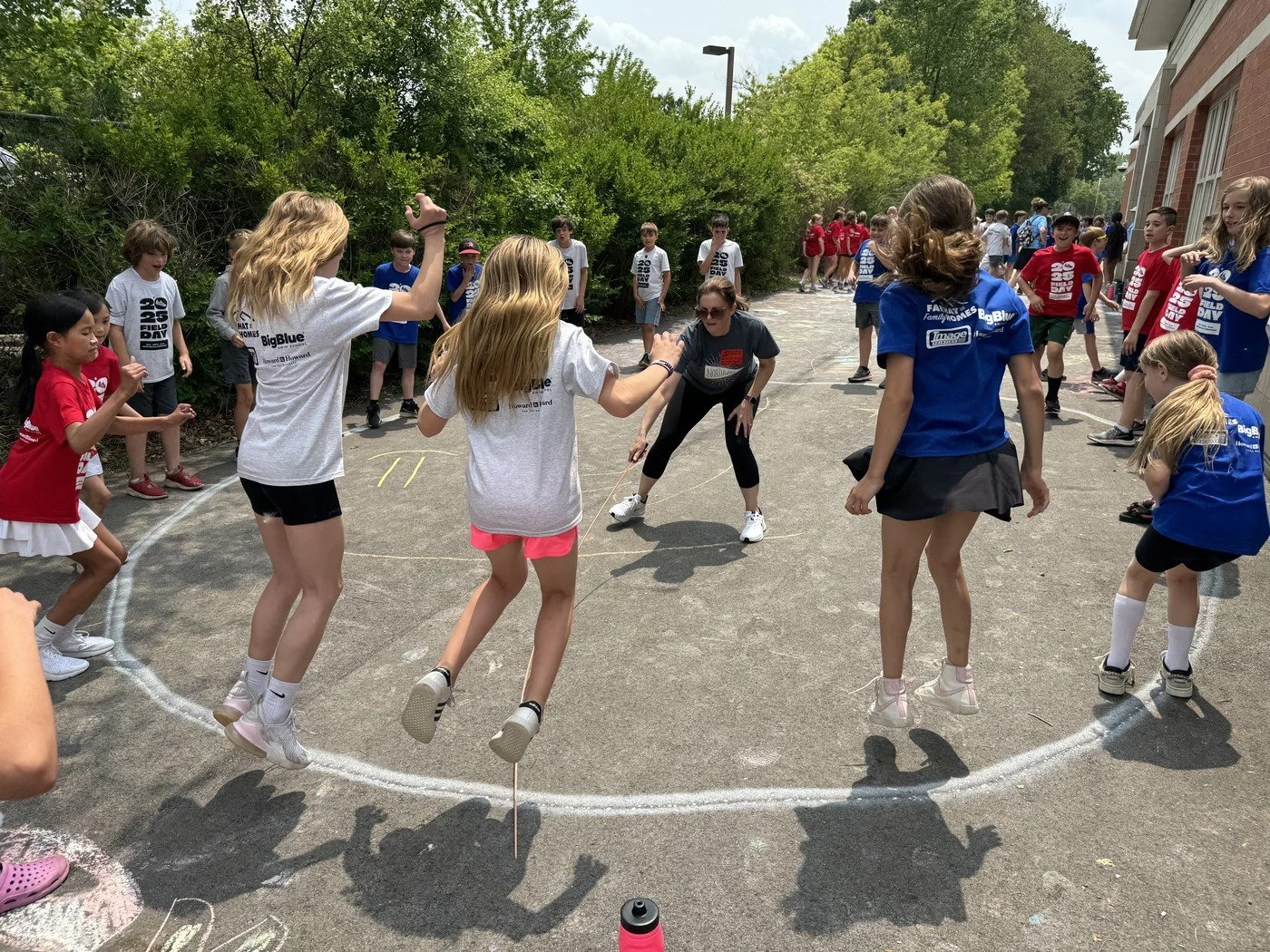 Children and adults participating in a jump rope activity outdoors during the Great American Field Day event, with some children jumping and others watching.