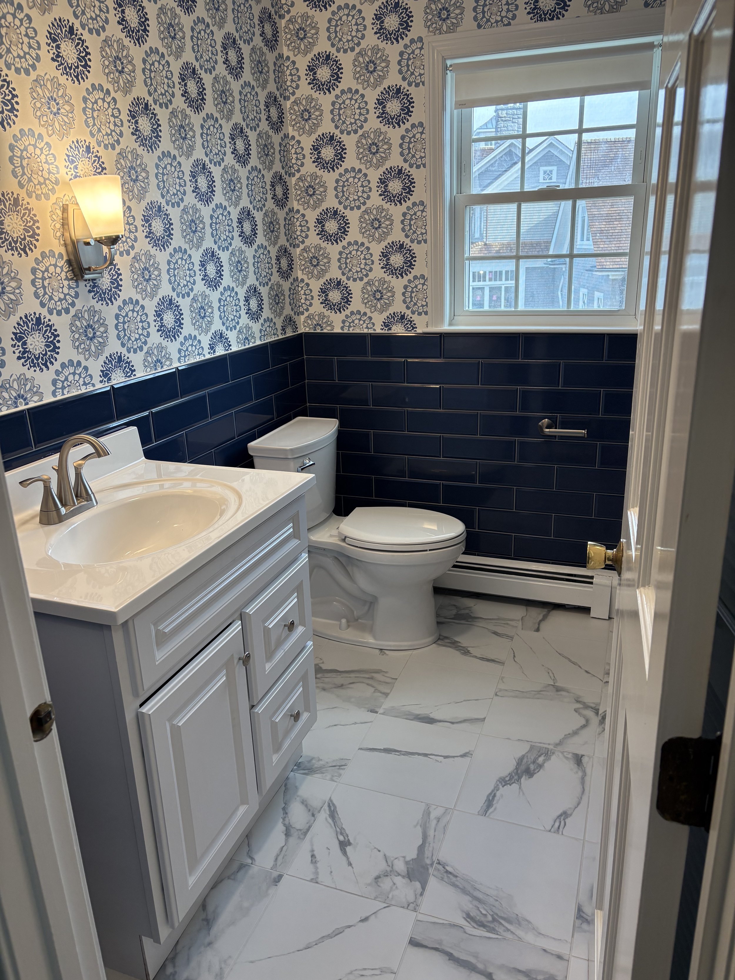 Glass-enclosed shower with light gray subway tile and pebble stone floor in Plymouth MA bathroom remodel