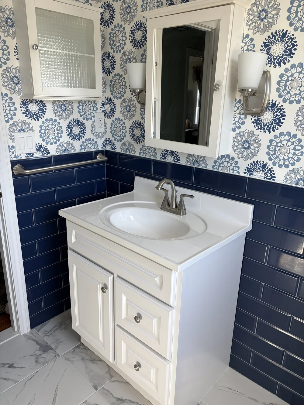 Marble-top vanity with geometric mirror in Plymouth, MA bathroom remodel by MSDG Construction