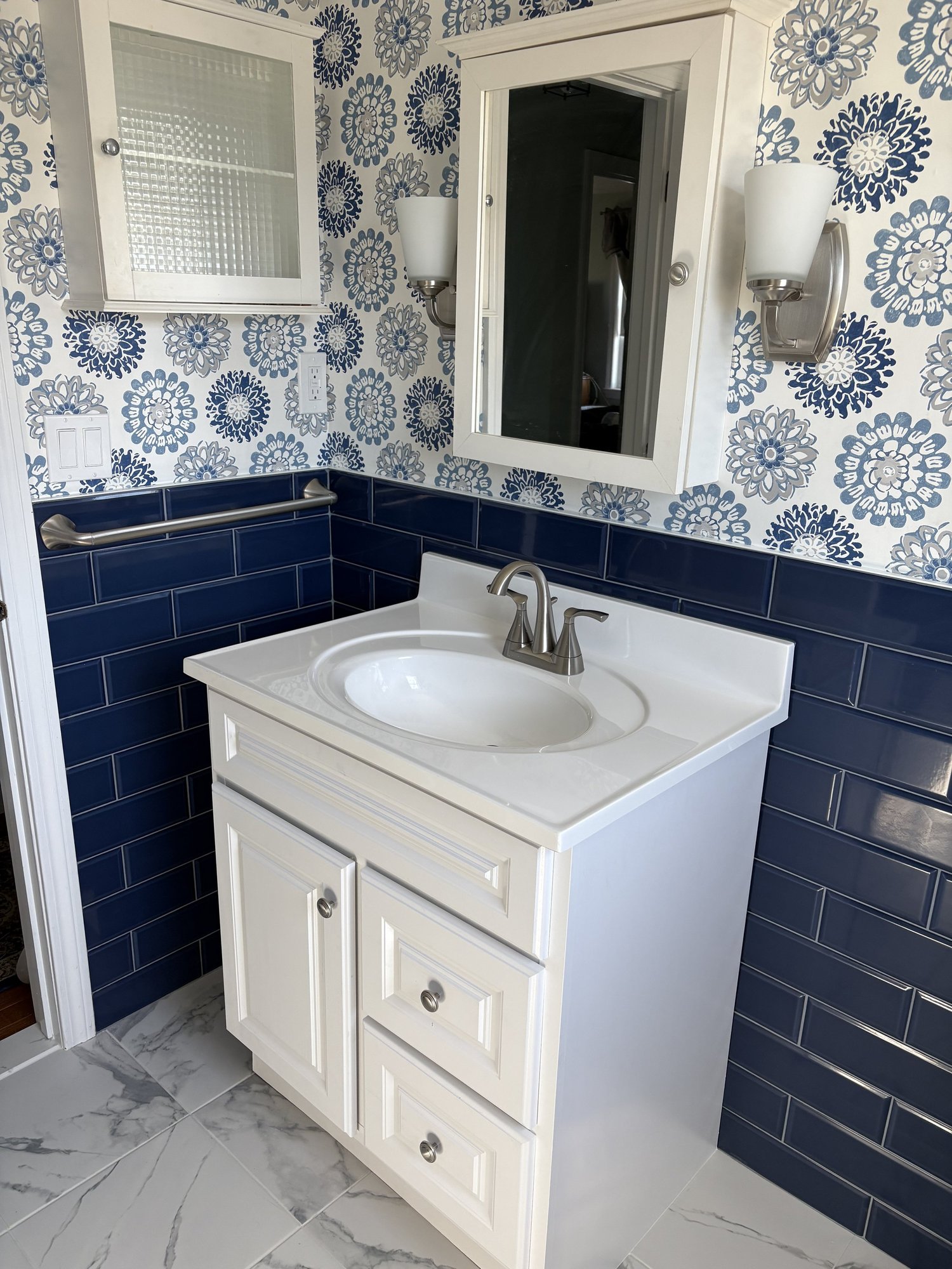 Custom marble-top bathroom vanity with geometric mirror by MSDG Construction in Plymouth, MA