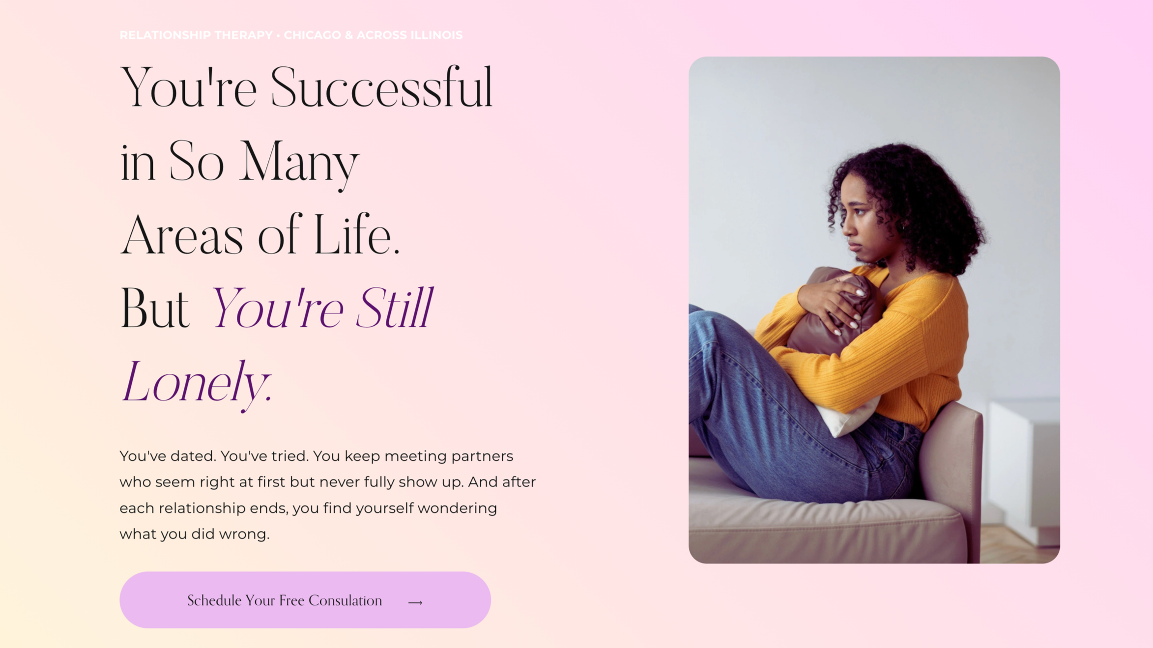 A woman sitting on a bed, hugging a pillow, looking thoughtfully to the side in a minimalist room with light-colored walls.