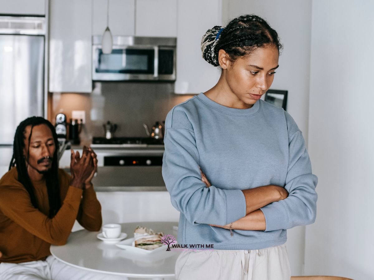 Woman looking away from her partner while he speaks to her at a kitchen table