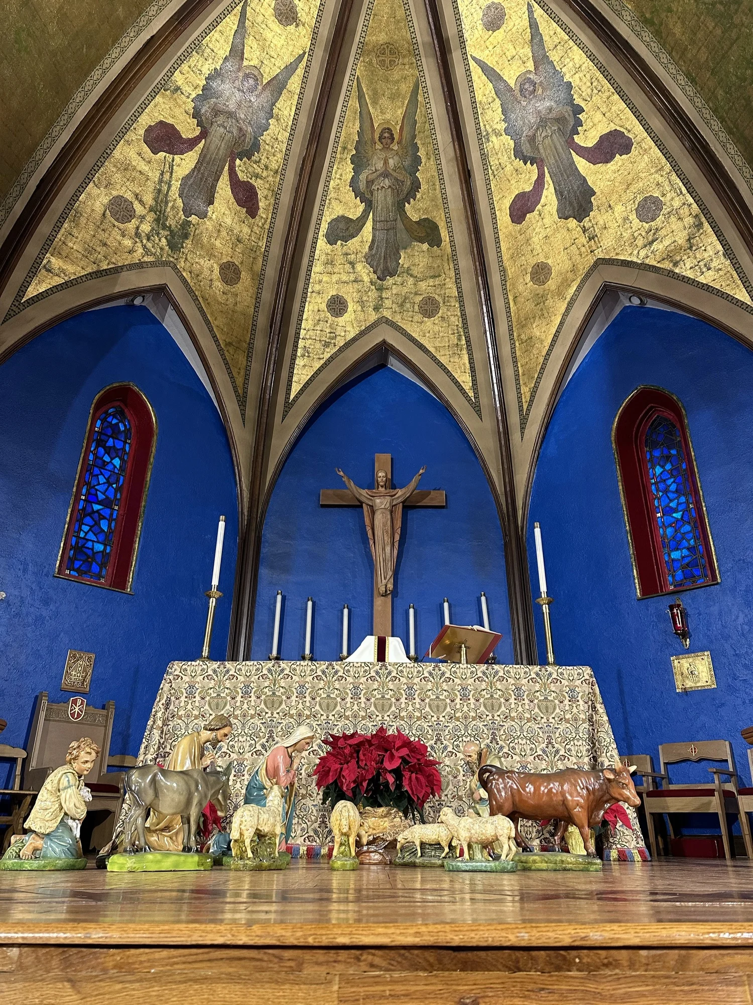 The nativity scene and poinsettias before the altar at St. John's on Christmas Eve, under the painted angels of the chancel