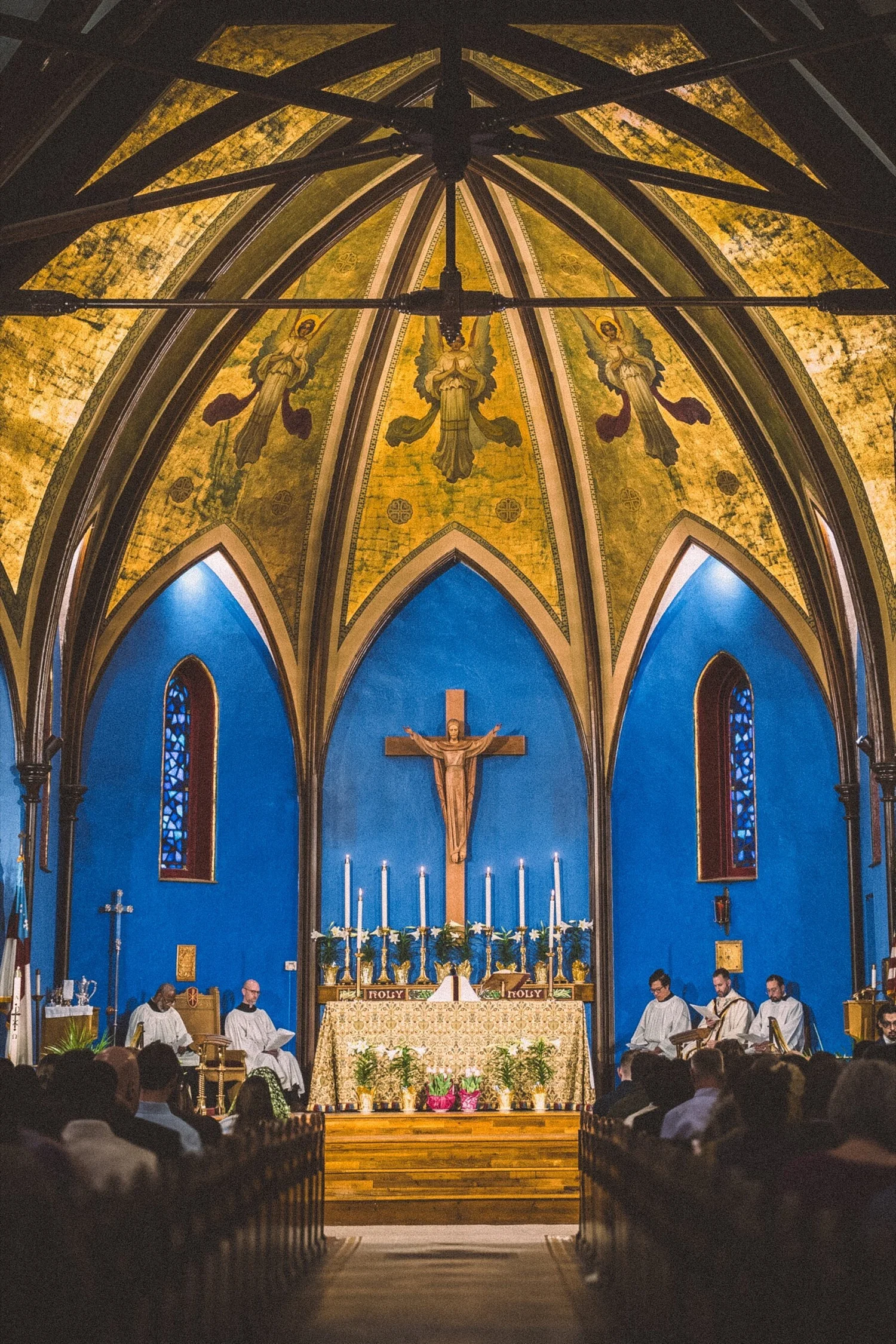 Easter Day at St. John's: lilies on the altar beneath the gold, angel-painted chancel, with the congregation in the pews