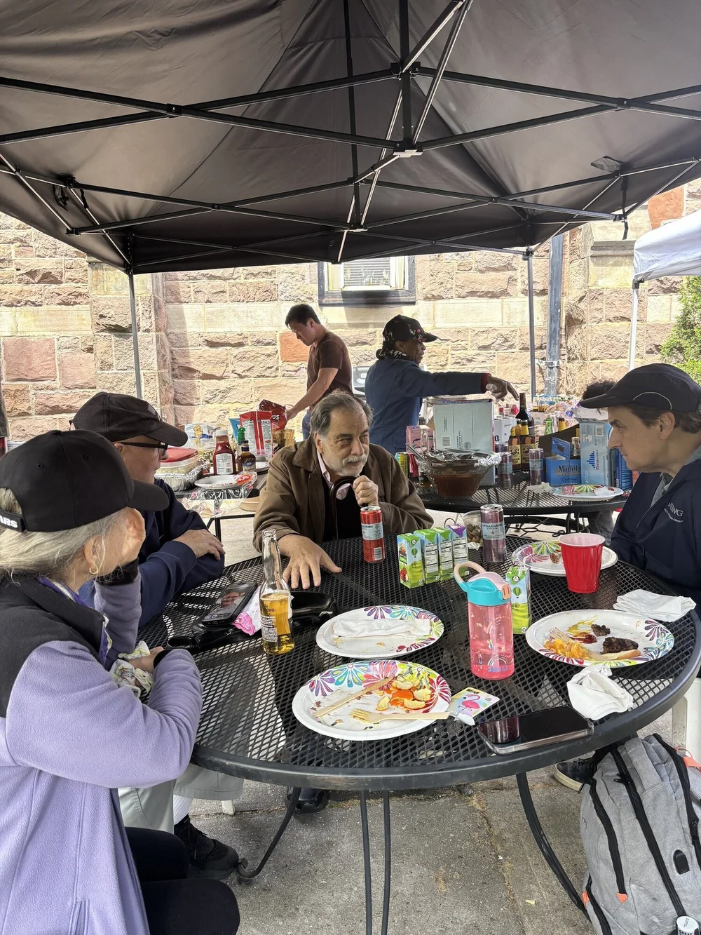 St. John's members sharing a cookout under tents in the church garden