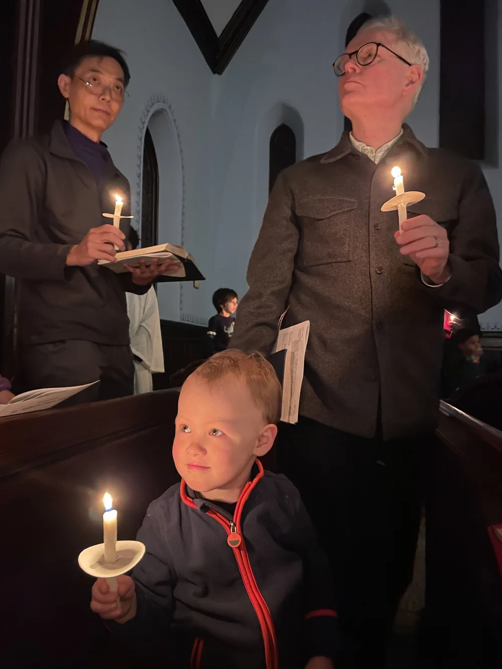 A young boy holding a lit candle during Silent Night on Christmas Eve at St. John's