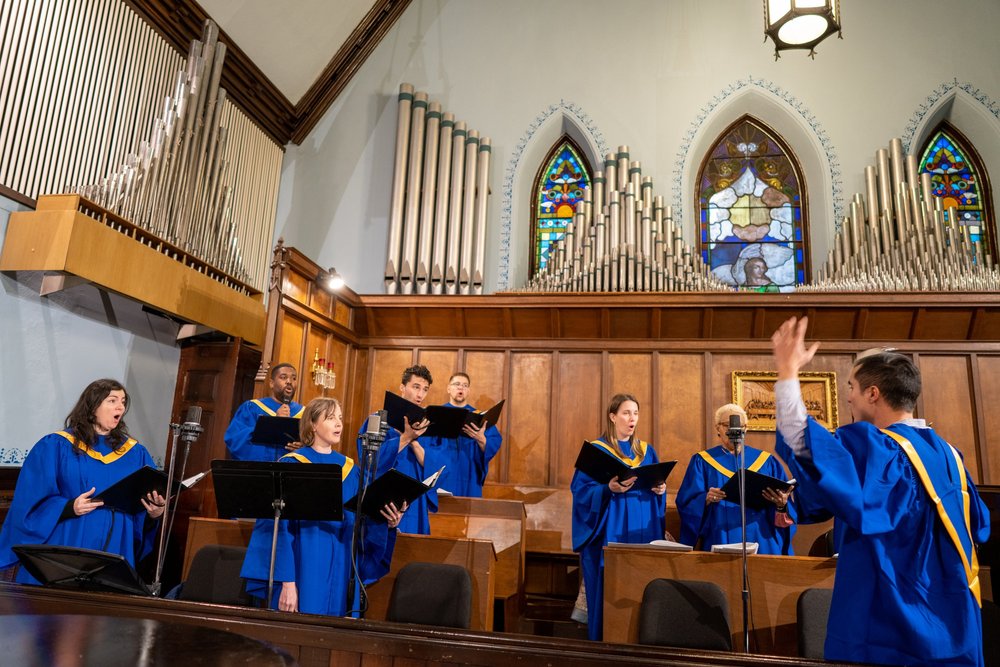 The St. John's choir in blue robes singing in the sanctuary