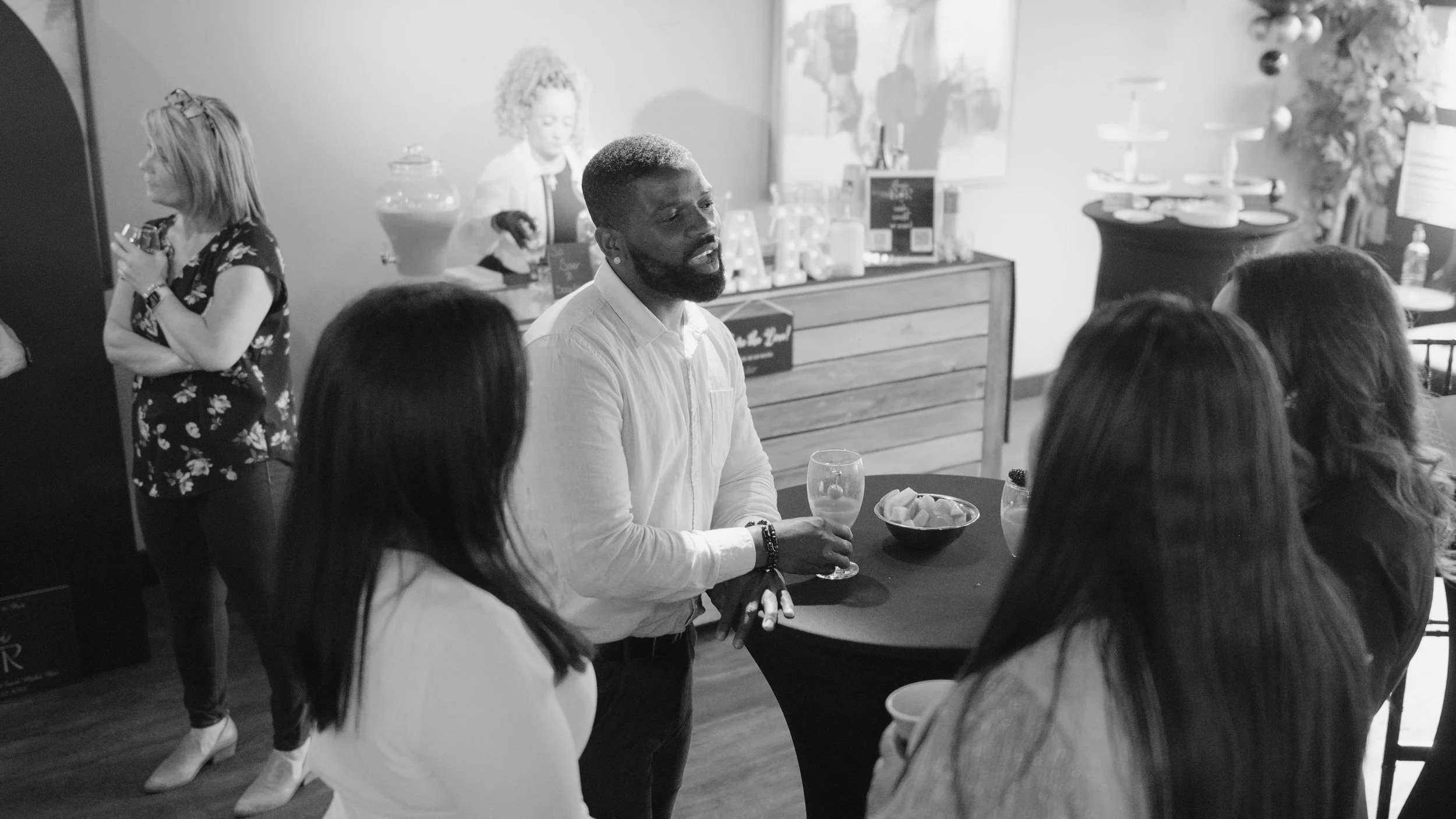 People socializing at an indoor event with drinks on a table.