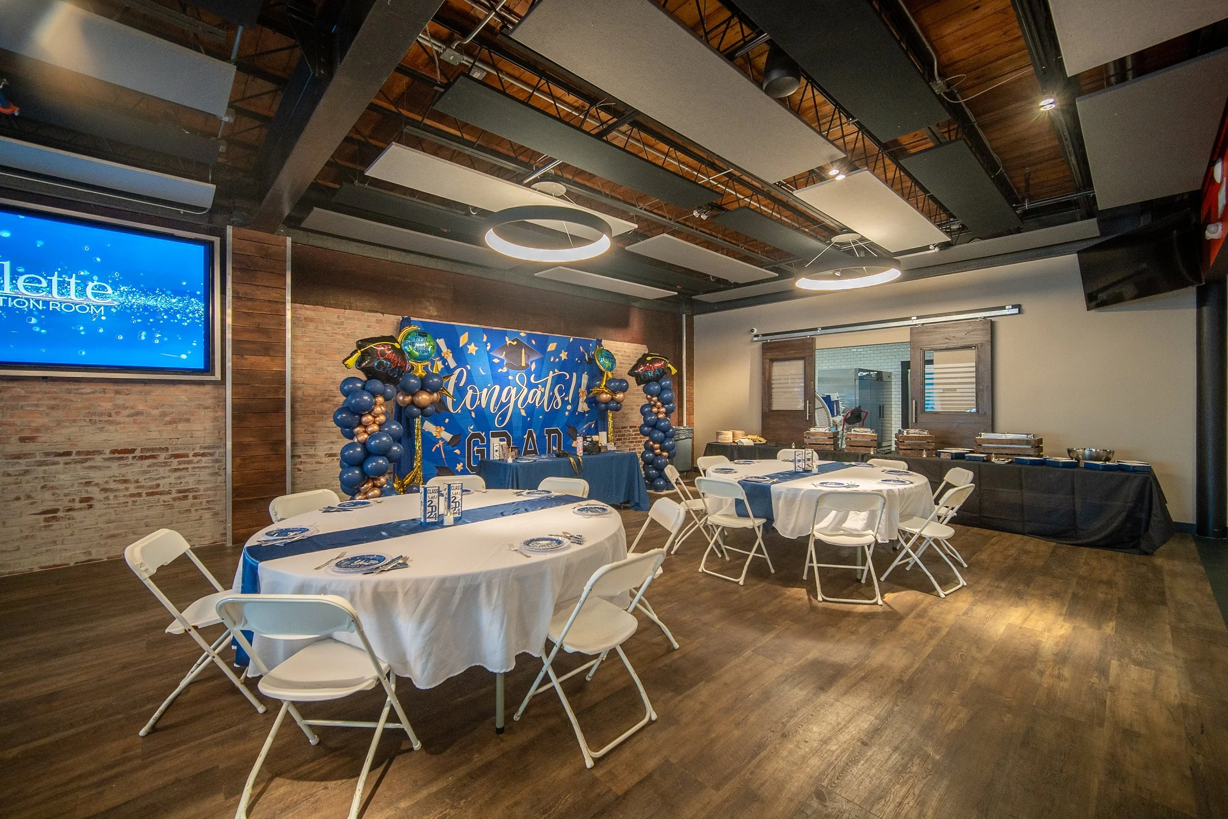 Graduation party setup with decorated tables, chairs, blue and gold balloons, and a "Congrats Grad" sign.