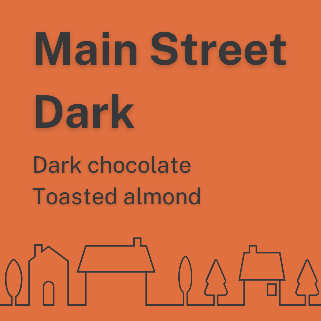 Orange background with black text indicating a menu item for "Main Street Dark," describing dark chocolate and toasted almonds, with simple black line drawings of houses and trees at the bottom.
