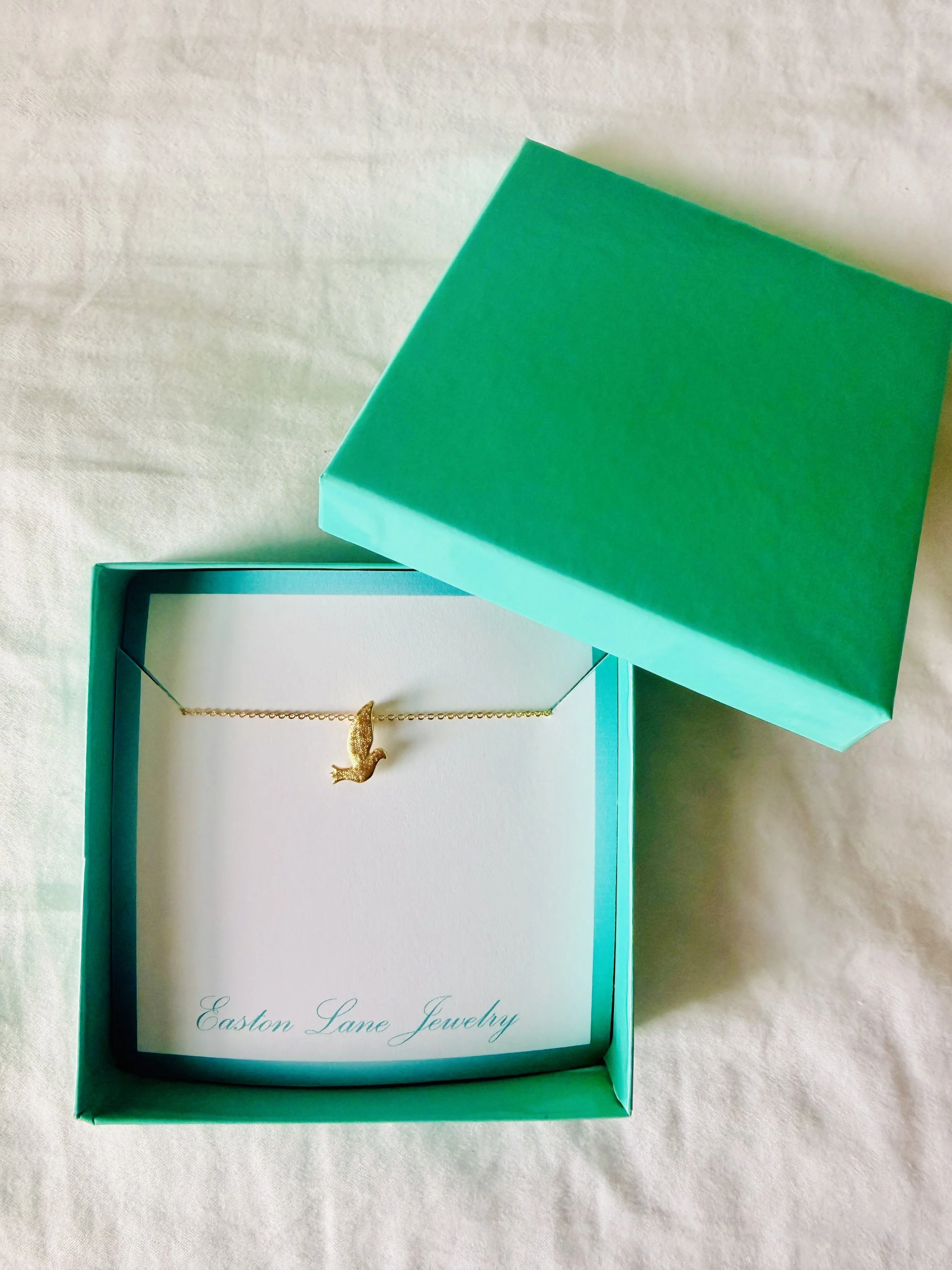image of a gold necklace with a bird pendant