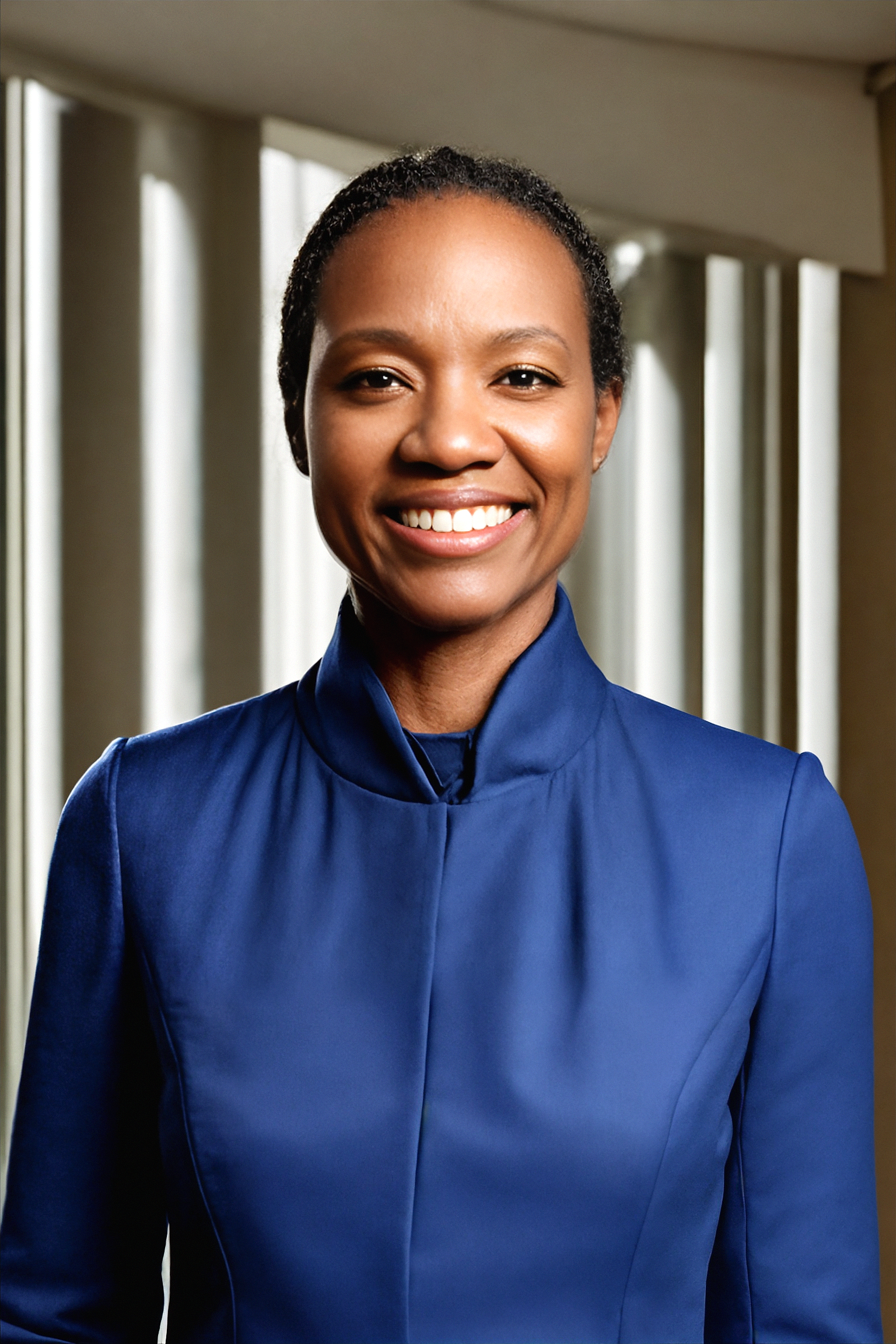 A close up portrait of Natasha Cook, PsyD, CPC, a clinical psychologist and coach smiling, wearing a blue satin blouse, looking directly at the camera.