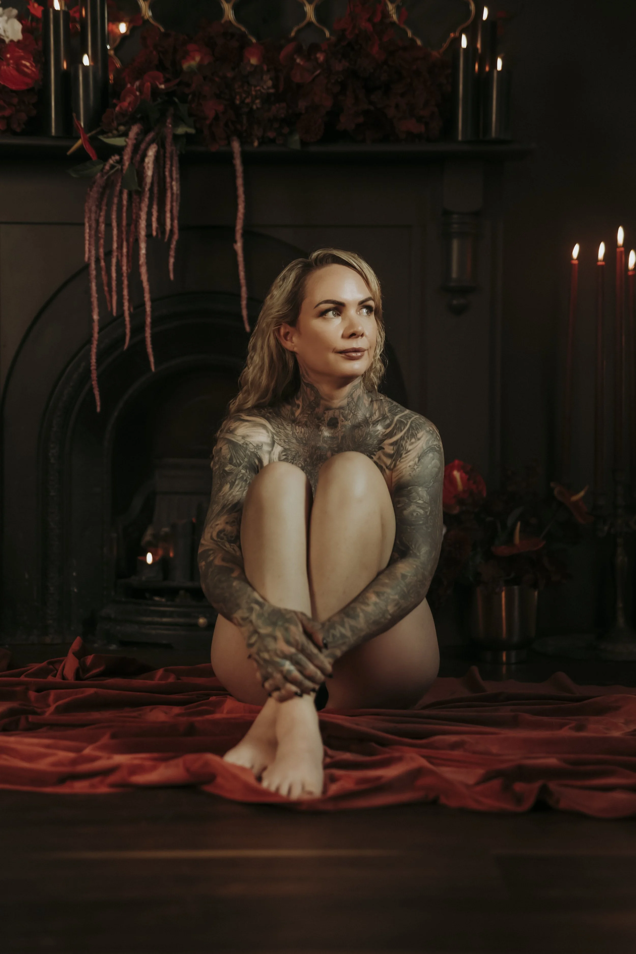 A woman in black lace lingerie posing on a bed in a cozy, rustic room with natural light streaming in.