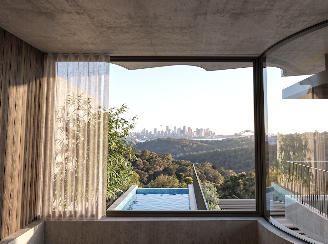 A view of a city skyline with a bridge and a tower in the distance, seen through a large window from an indoor space with wooden and concrete finishes, and a small pool outside.