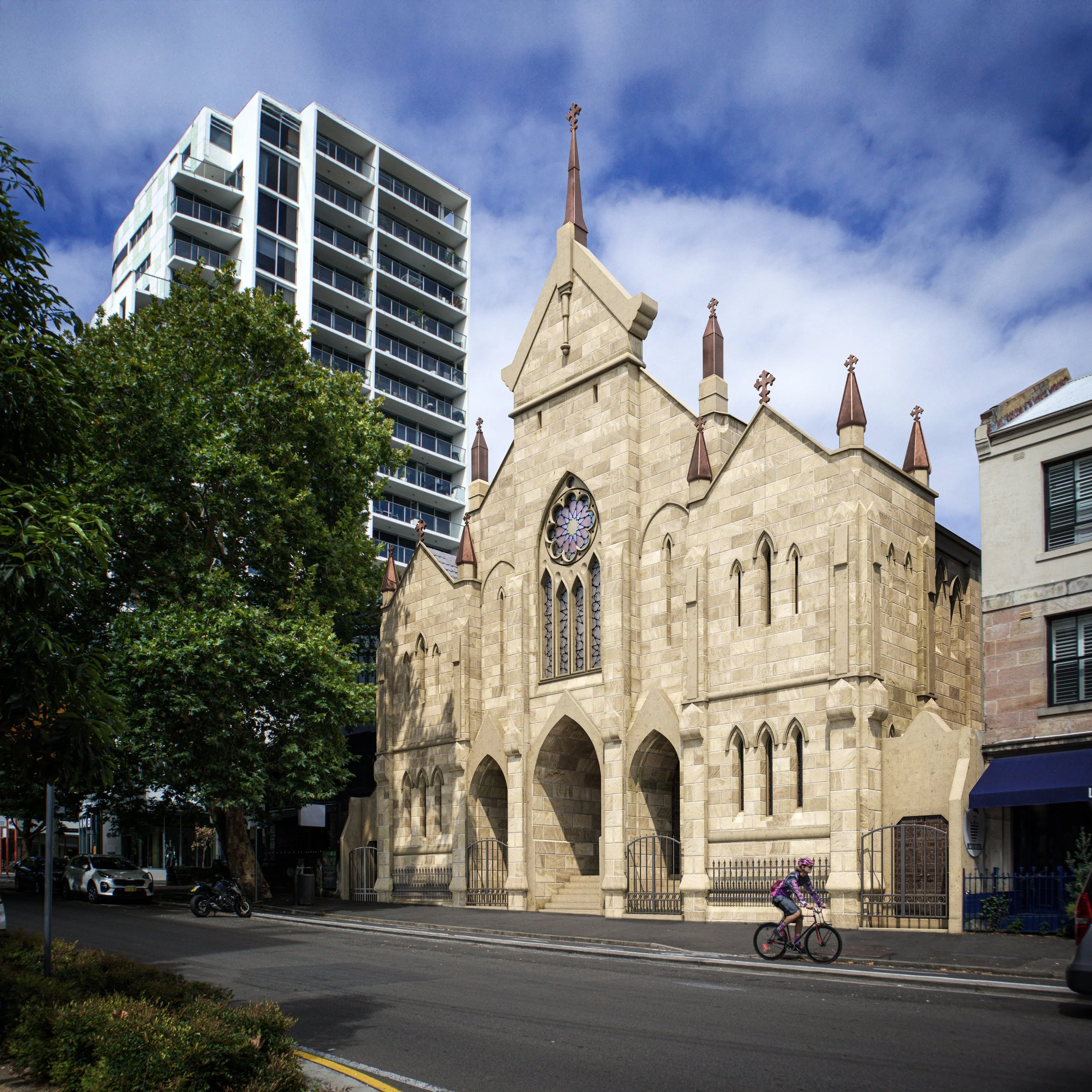 A street scene showing a large historic church with gothic architecture and stained glass windows in the foreground, and a modern high-rise apartment building in the background. There are trees, parked cars, and a pedestrian riding a bicycle on the s