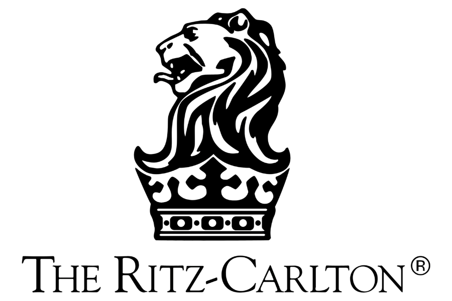 Outline of a lion's head with flowing mane, placed above a decorative base, representing The Ritz-Carlton luxury hotel brand.