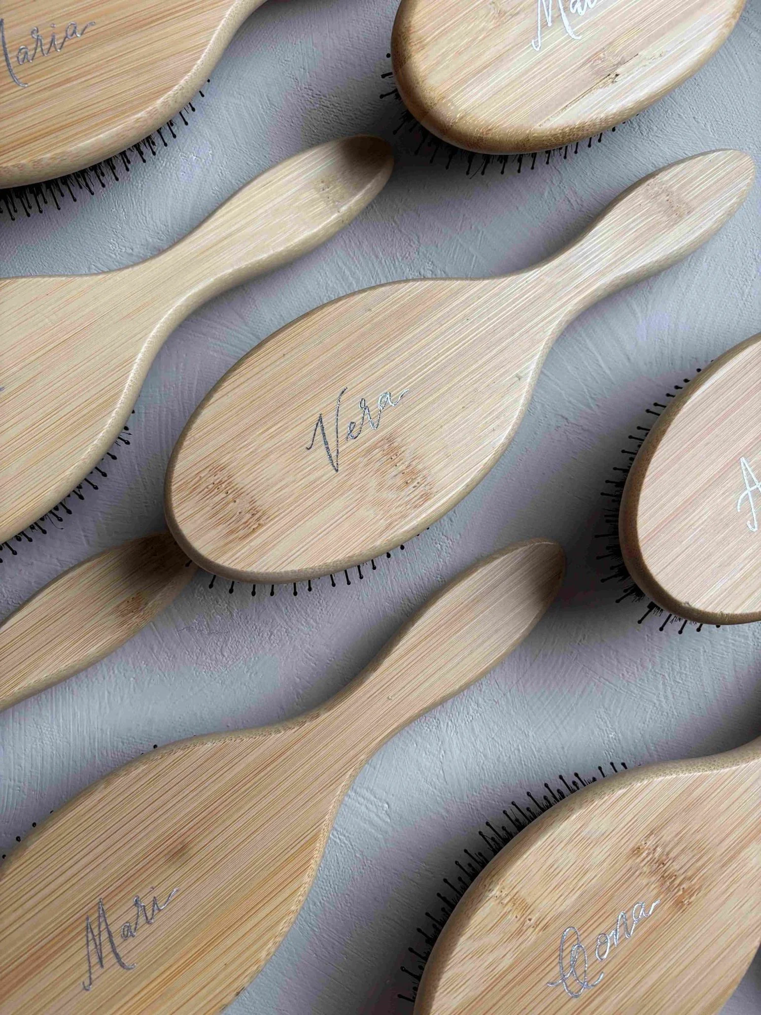 Hiusharjoja pöydällä, hiusharjoissa naisten nimiä kirjoitettuna kuumafoliolla.