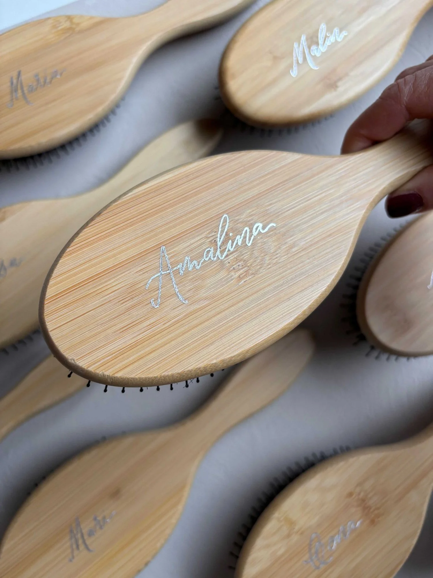 Hopeanvärisellä kuumafoliolla kirjoitettu etunimi Ibero bambuharjan pinnalla.