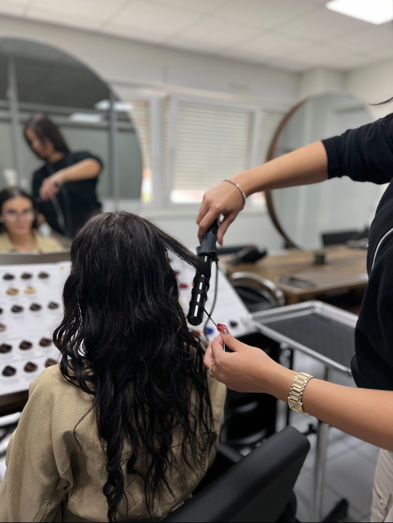 Un coiffeur boucle les cheveux d'une cliente dans un salon de coiffure.