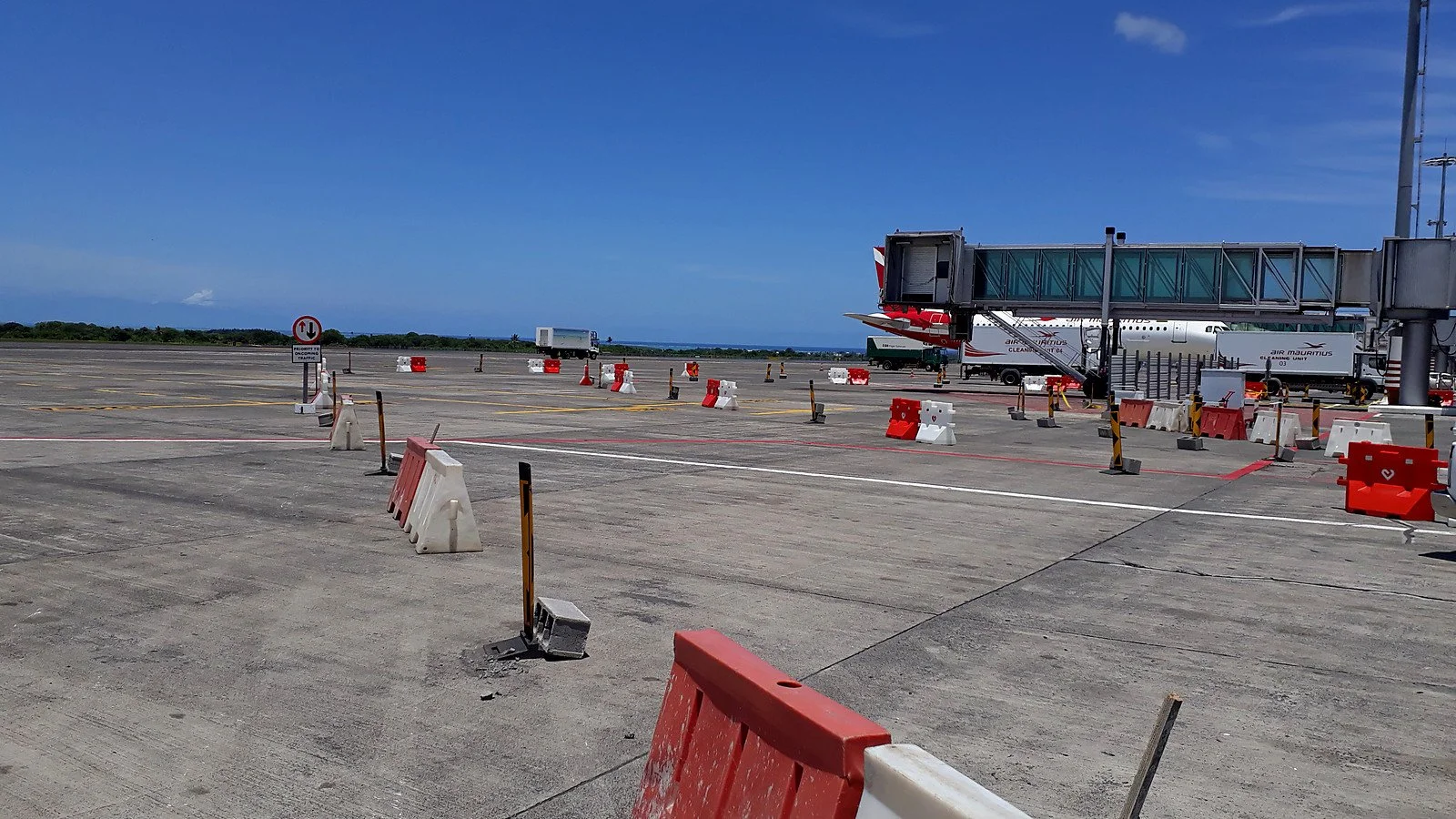 Construction-stage view of the terminal facade and passenger boarding bridge interface within the operational airport environment.
