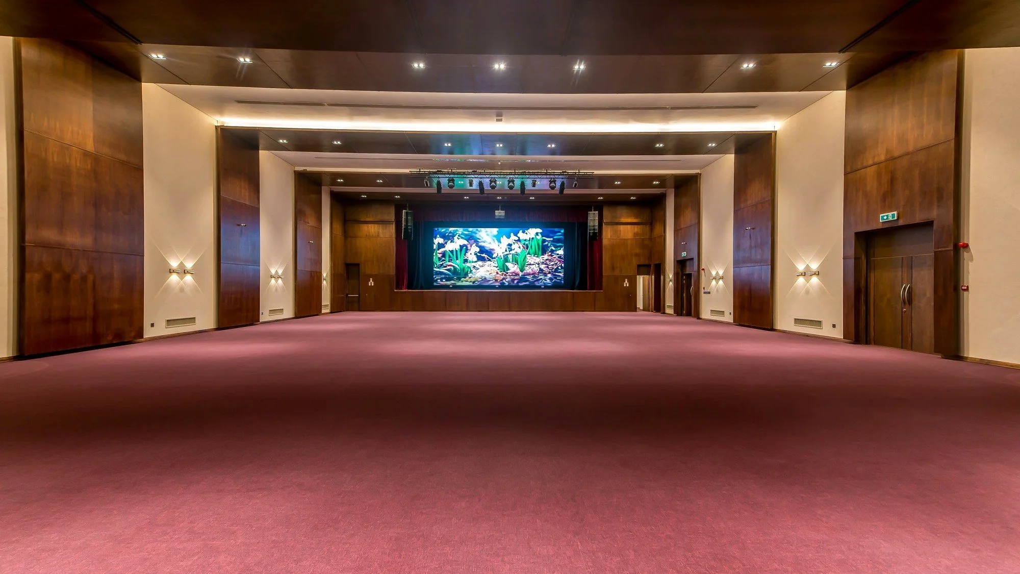 Multipurpose hall with timber wall finishes, integrated lighting and a presentation stage