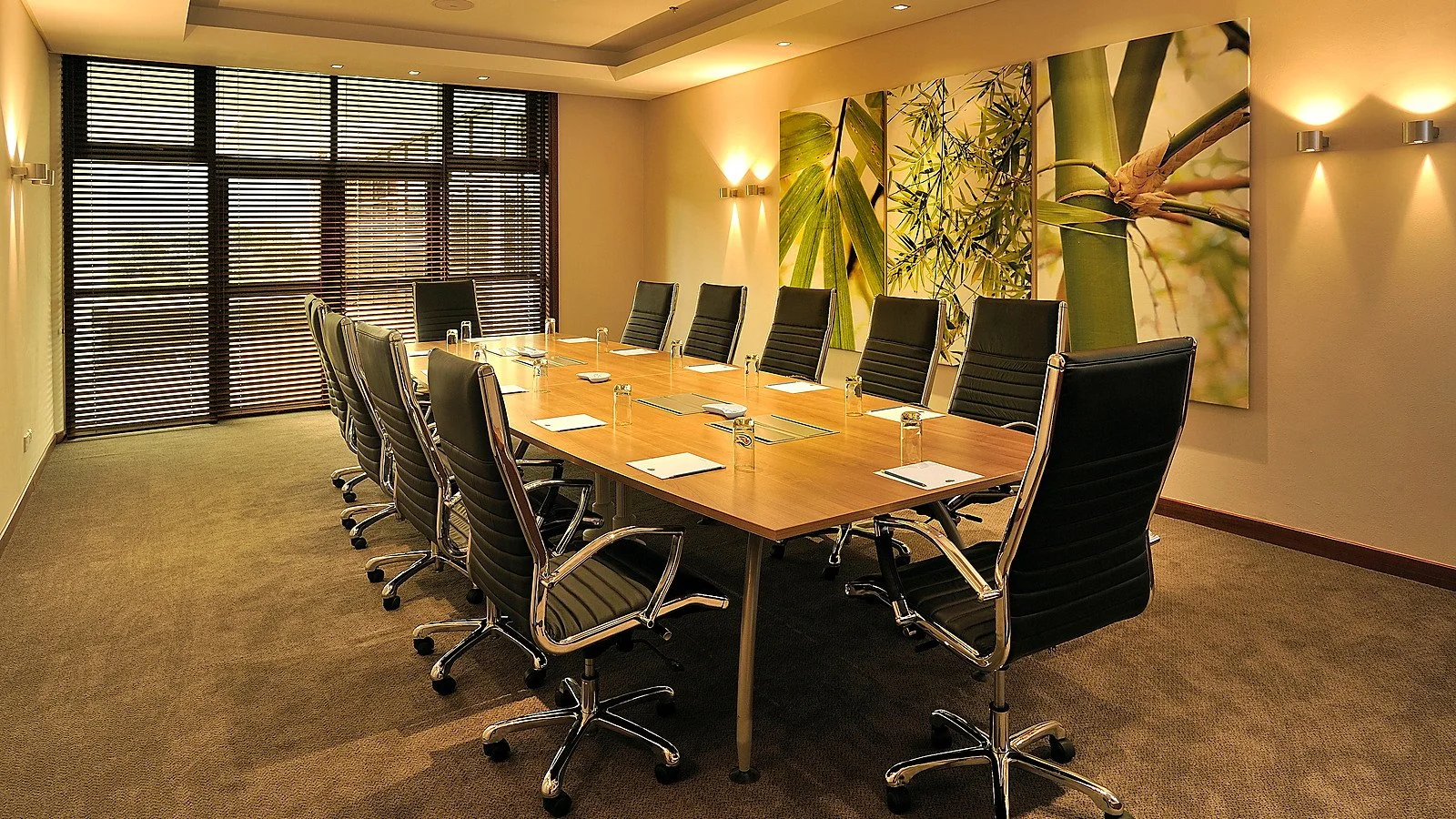 Completed hotel conference room arranged with a central meeting table, presentation seating and integrated lighting.