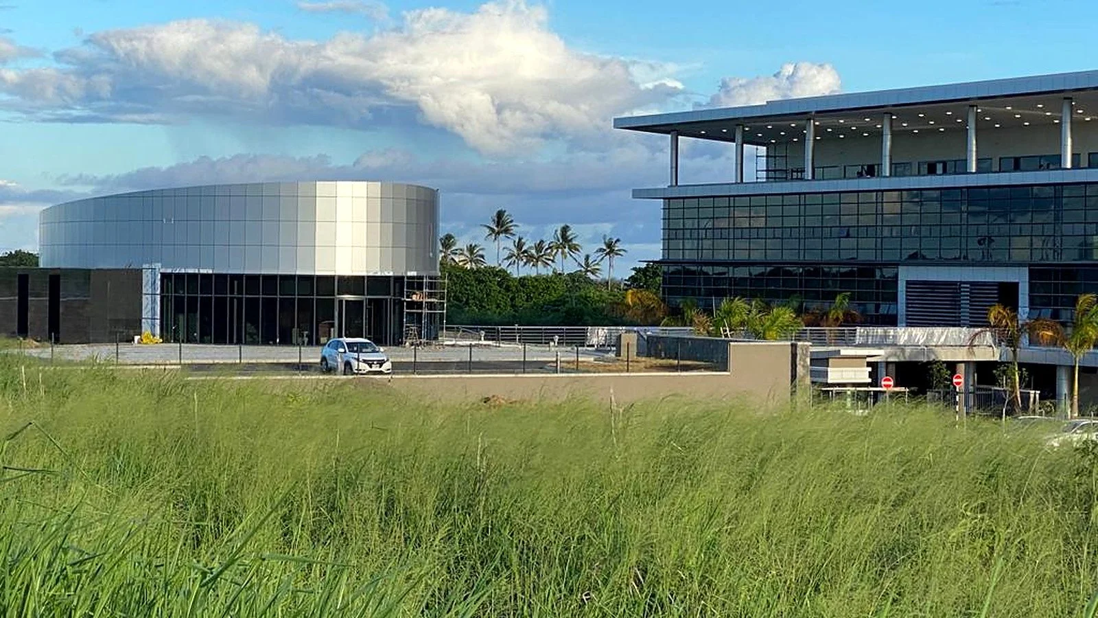 Wide view of the ICCC campus showing the curved auditorium alongside the main glazed administration building.