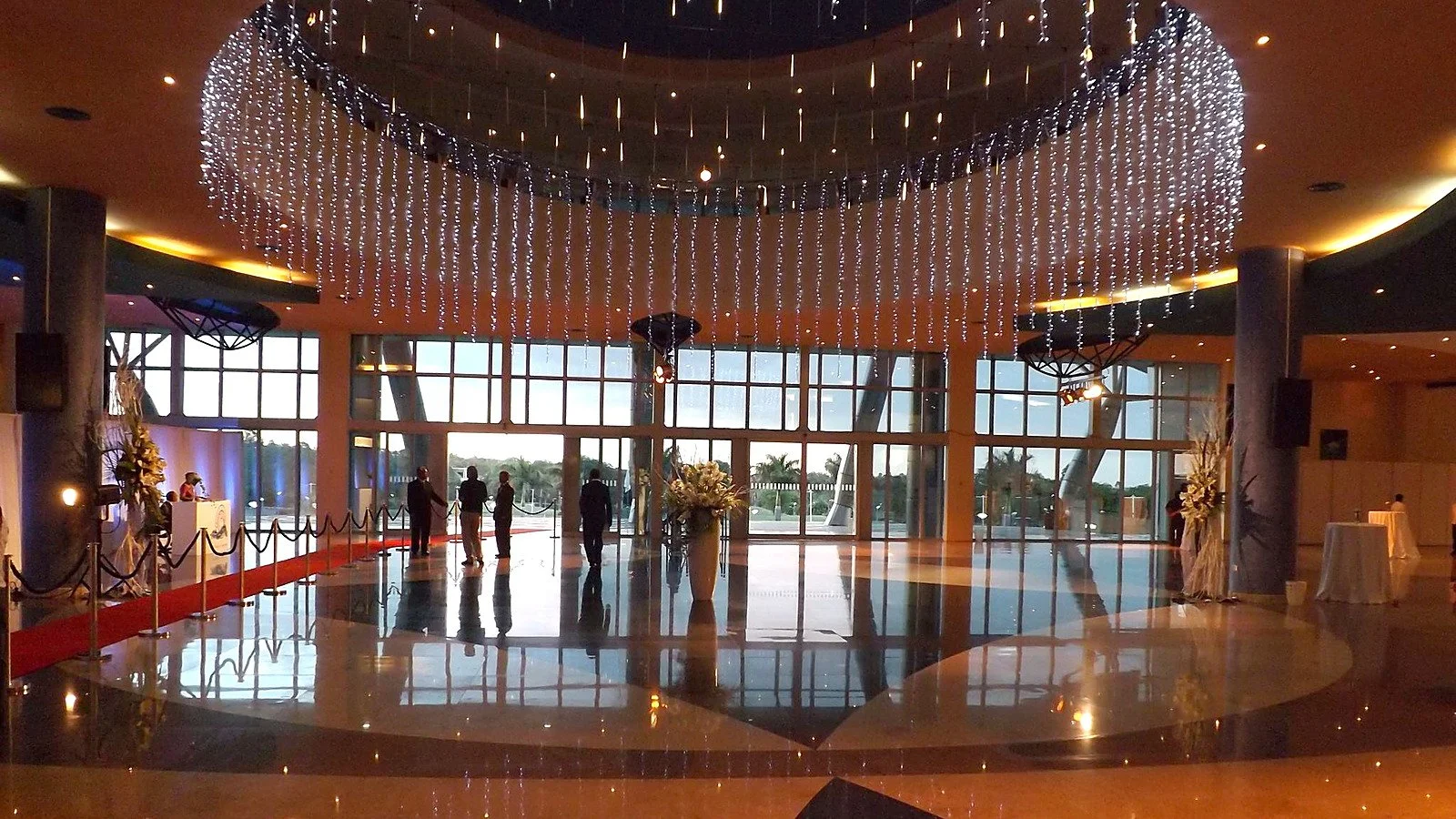 Completed main foyer and atrium with a polished floor, glazed entrance and suspended decorative lighting prepared for an event.