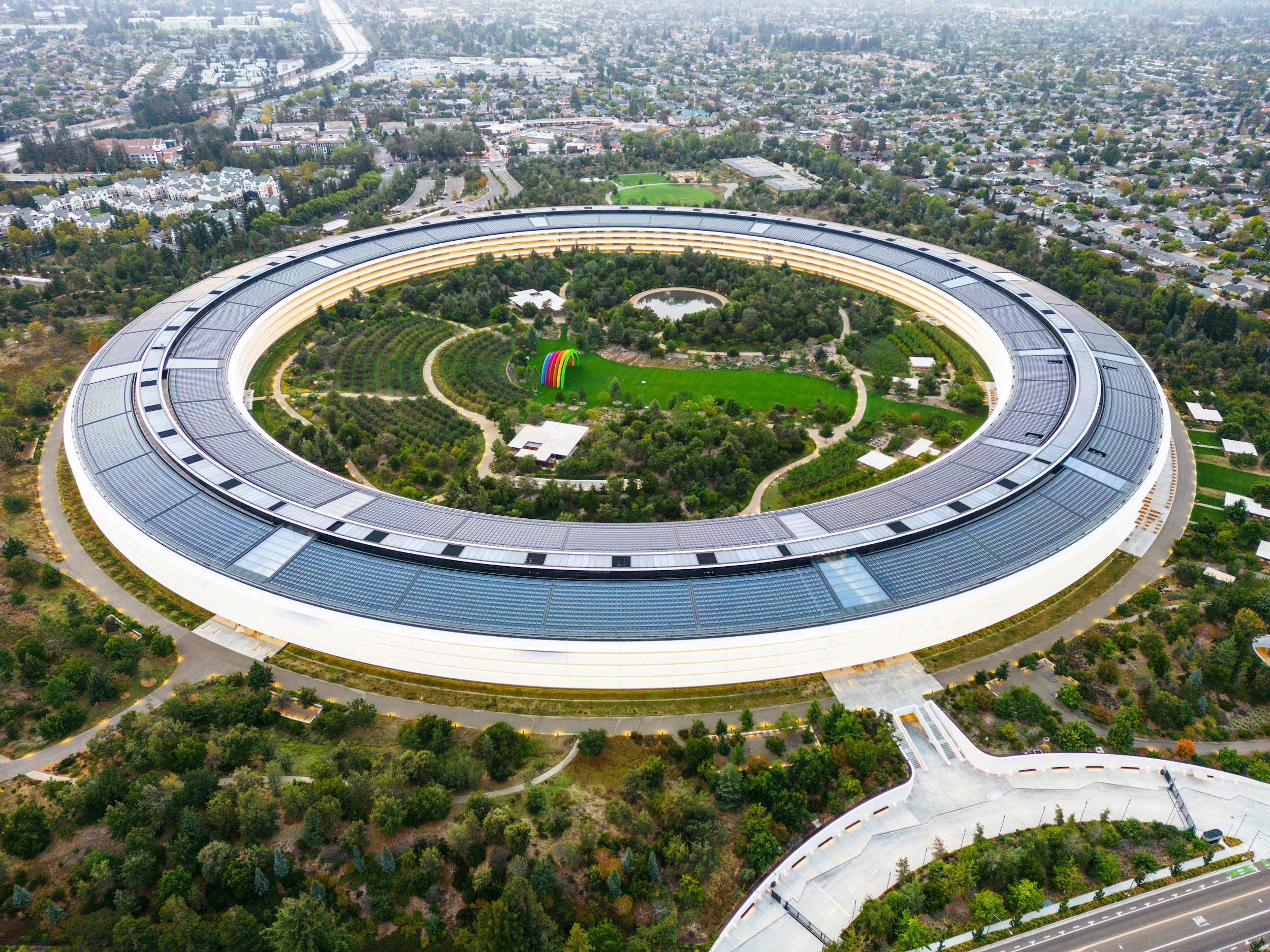 Aerial view of a large, circular building with a green park inside, surrounded by trees and city streets.