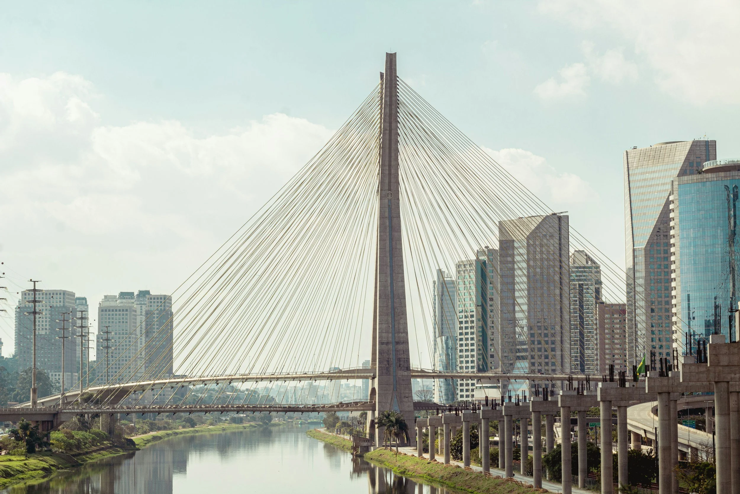 City skyline featuring a modern cable-stayed bridge over a river with high-rise buildings in the background.