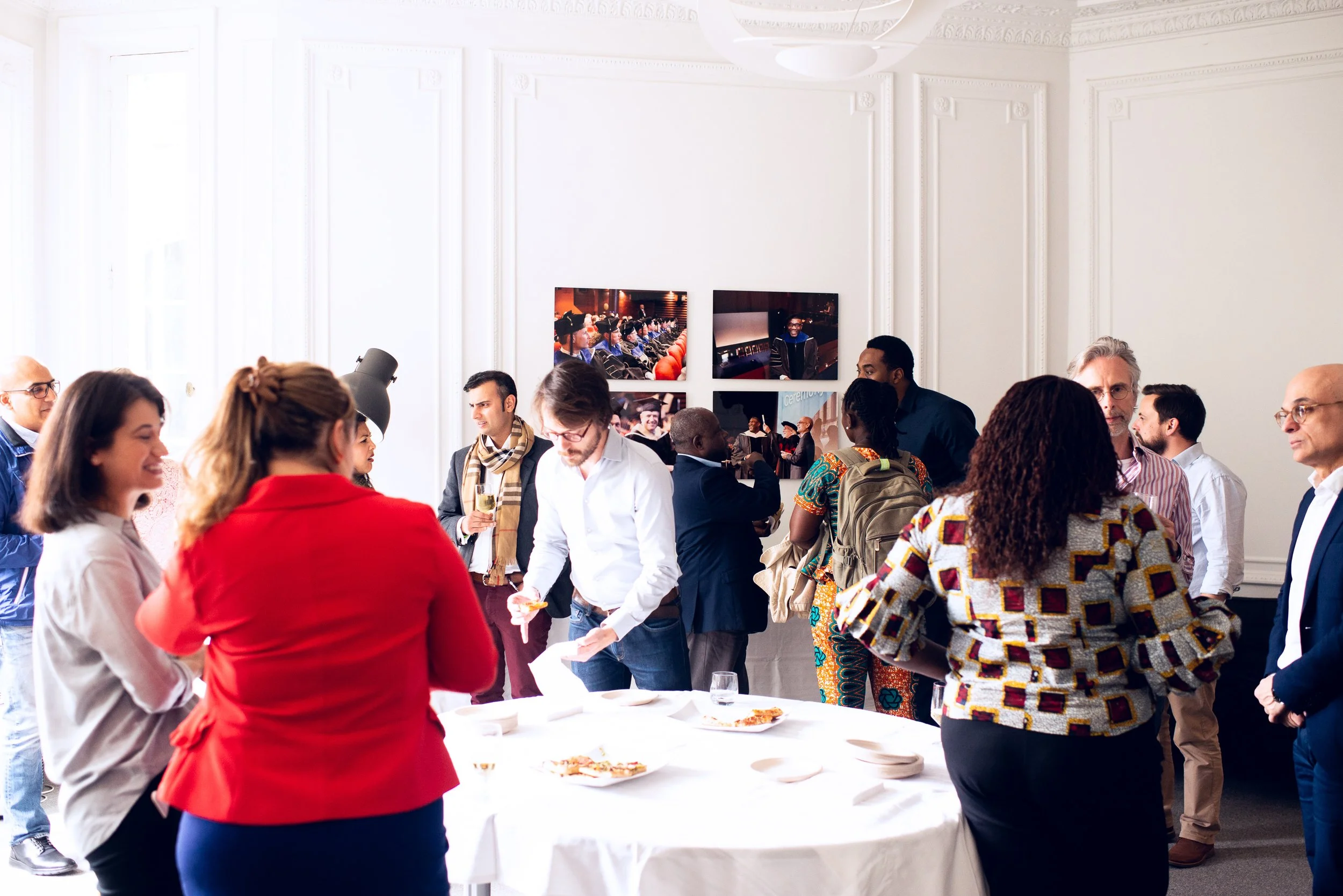 Group of diverse people socializing and having pizza at a professional gathering or conference in a bright, elegant room.