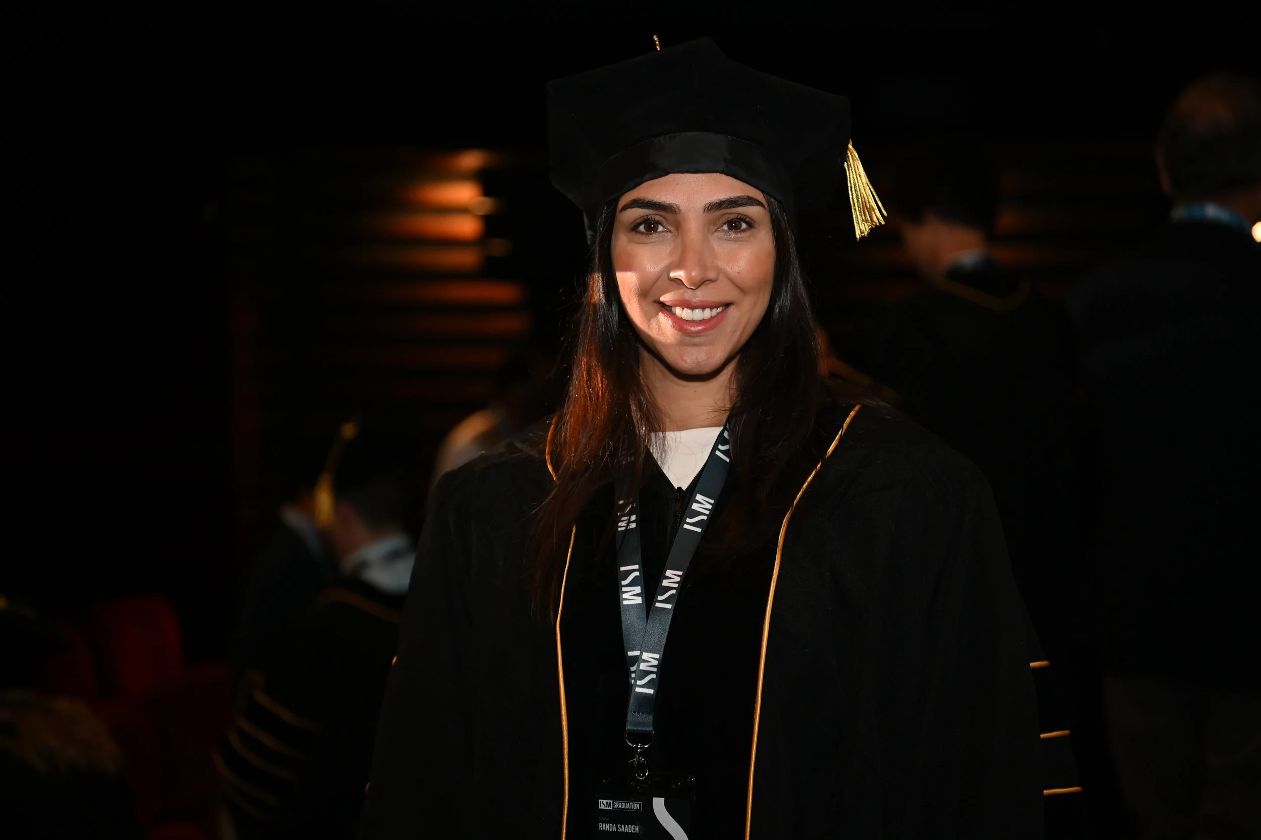 Young woman in graduation cap and gown smiling at a graduation ceremony.