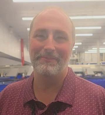 Person smiling, wearing a black polo shirt