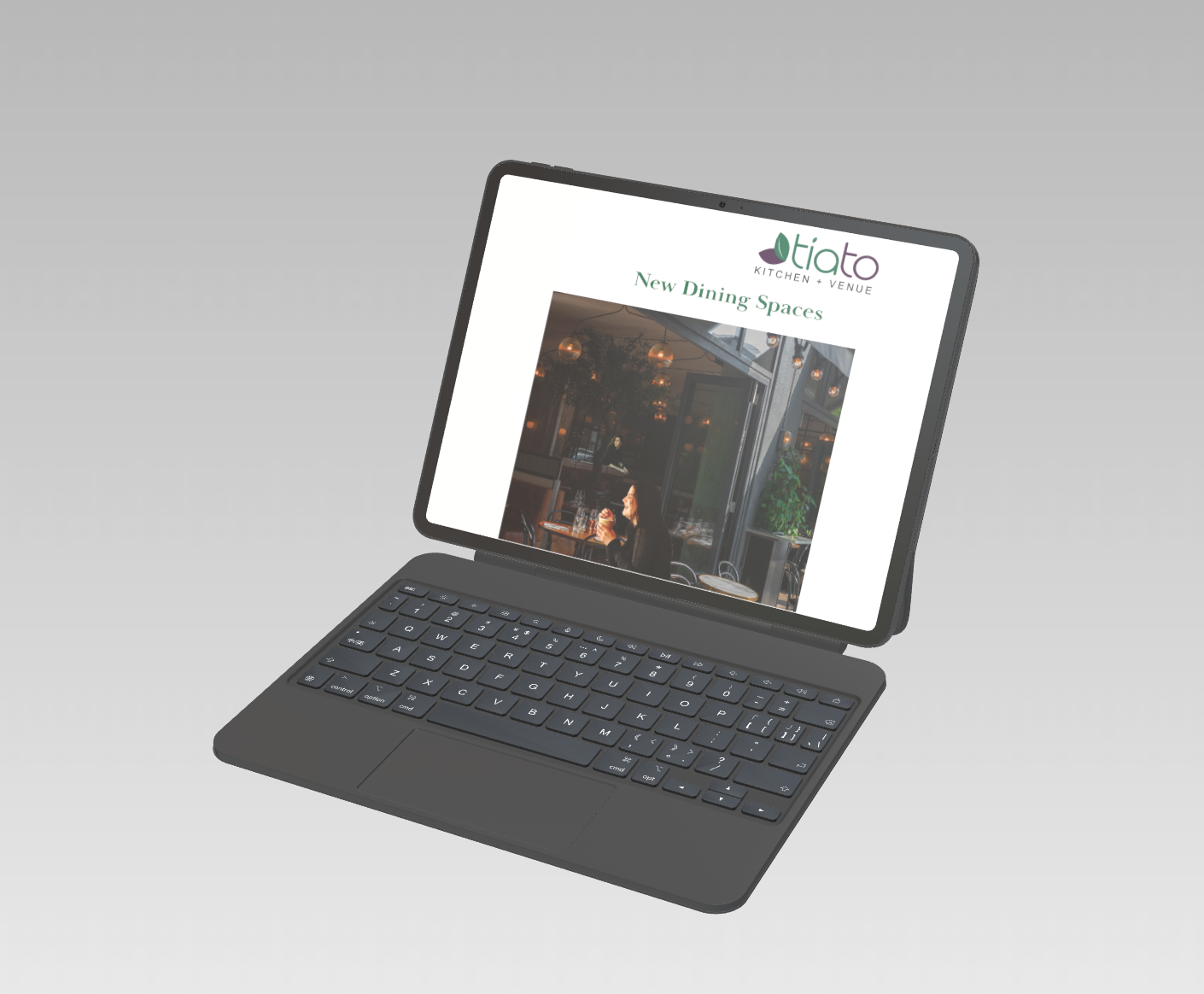 A tablet with a detachable keyboard displaying a website for Tia Tio Kitchen + Venue, advertising new dining spaces, with an image of a woman dining inside the restaurant.