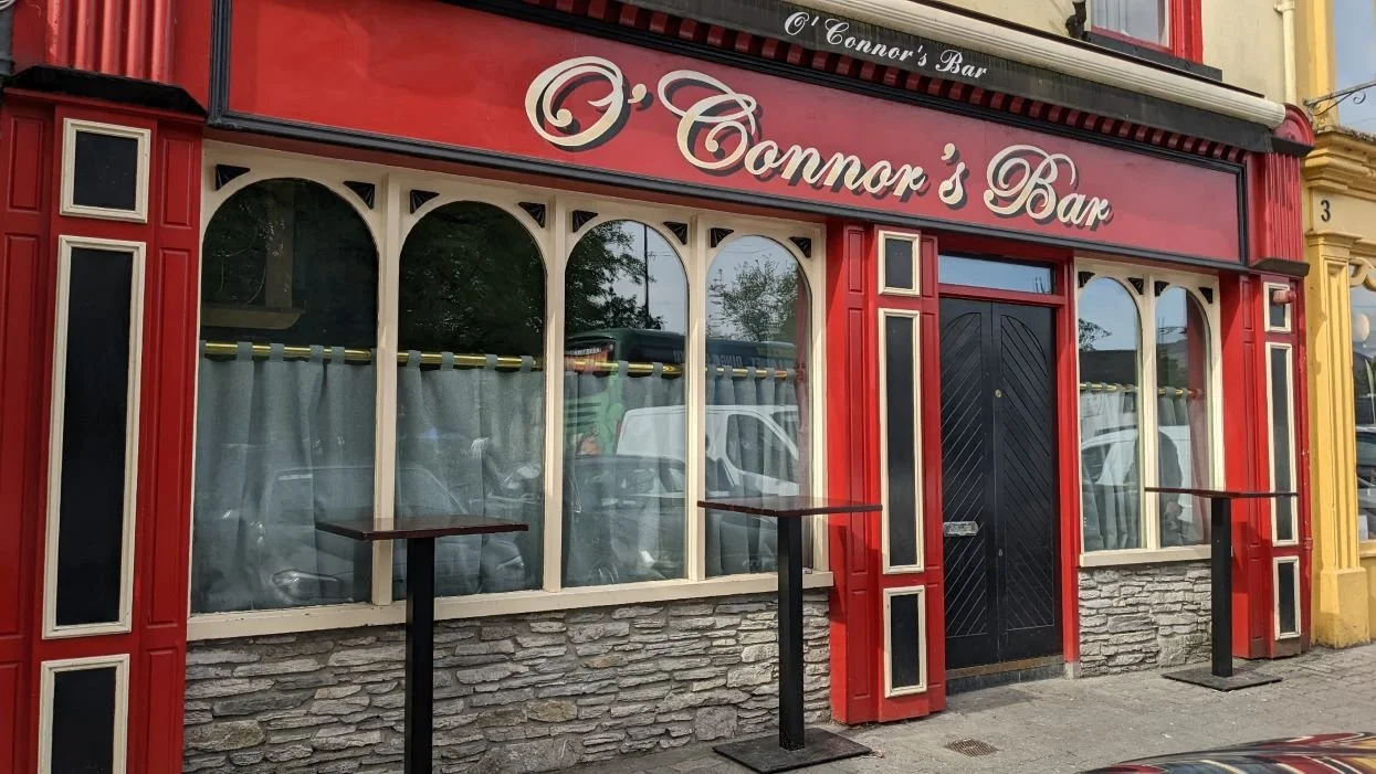 Exterior of O'Connor's Bar with red and cream facade and arched windows.