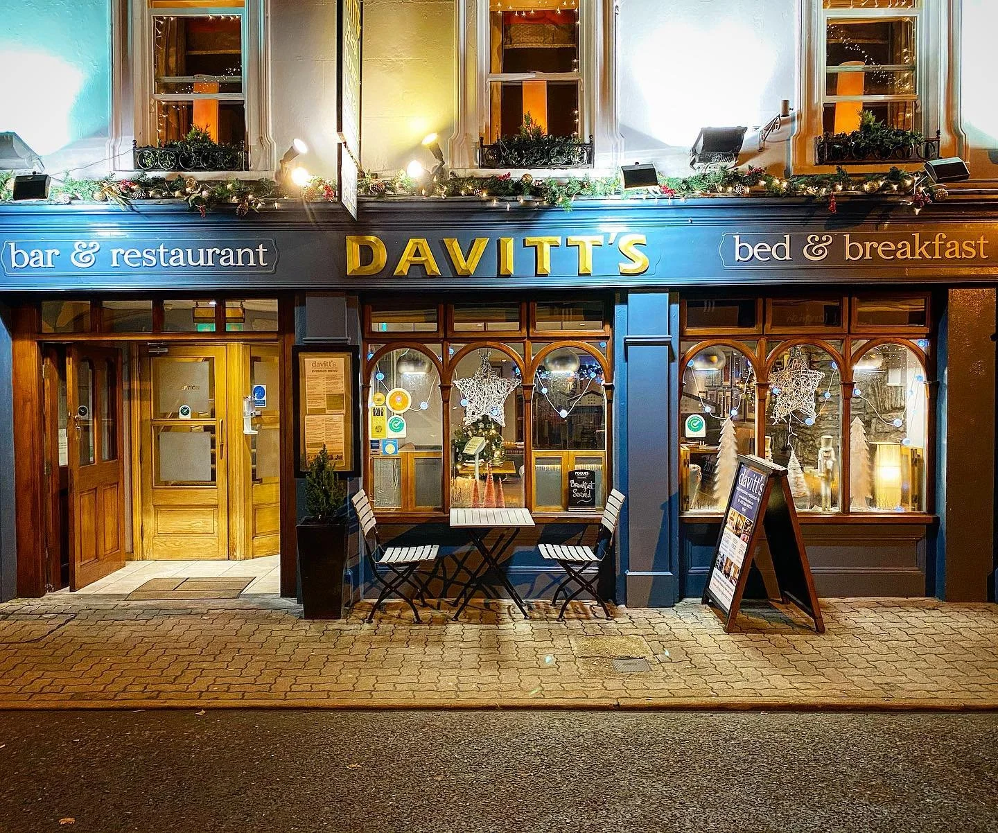 Facade of Davitt's Bar, Restaurant, and Bed & Breakfast, featuring outdoor seating and festive decorations.