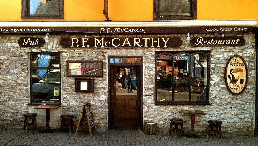 Exterior of P.F. McCarthy pub and restaurant with stone facade, signage, and outdoor seating.