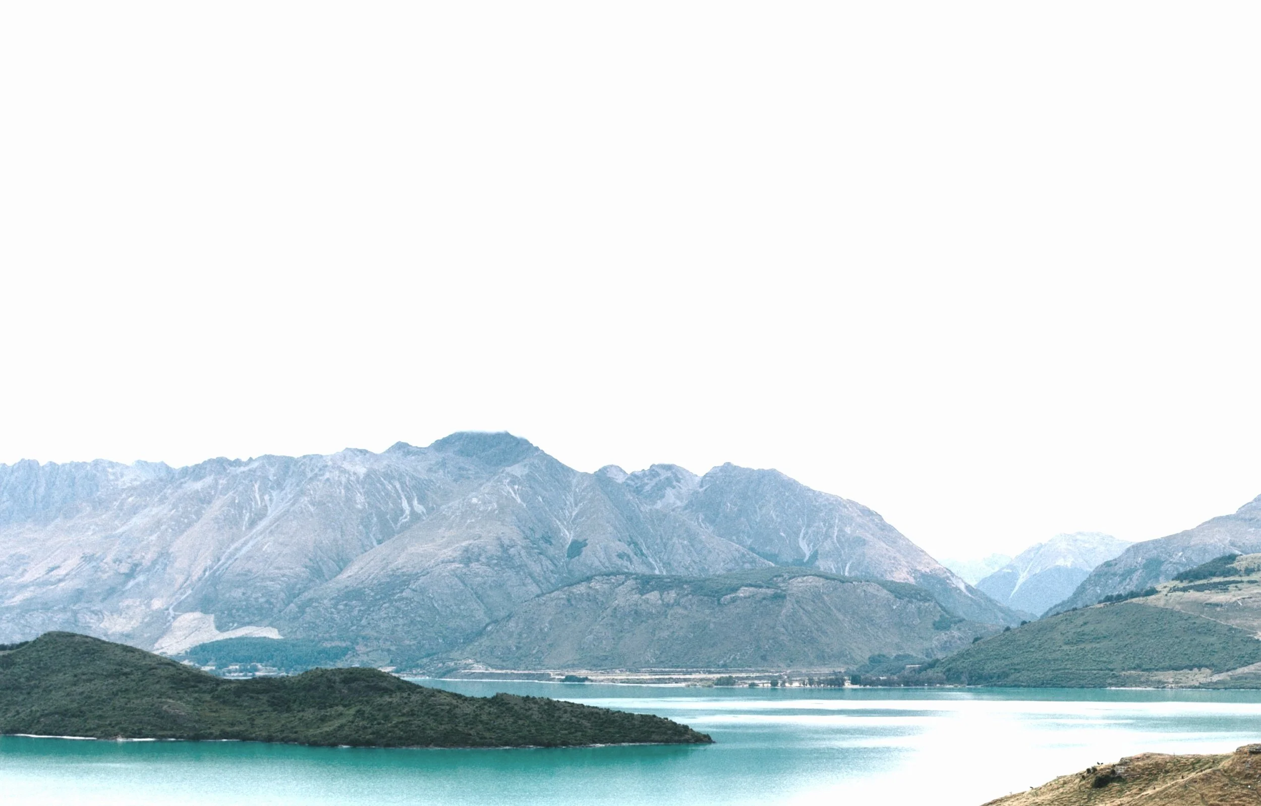 Mountains with rocky peaks and a body of water in the foreground.