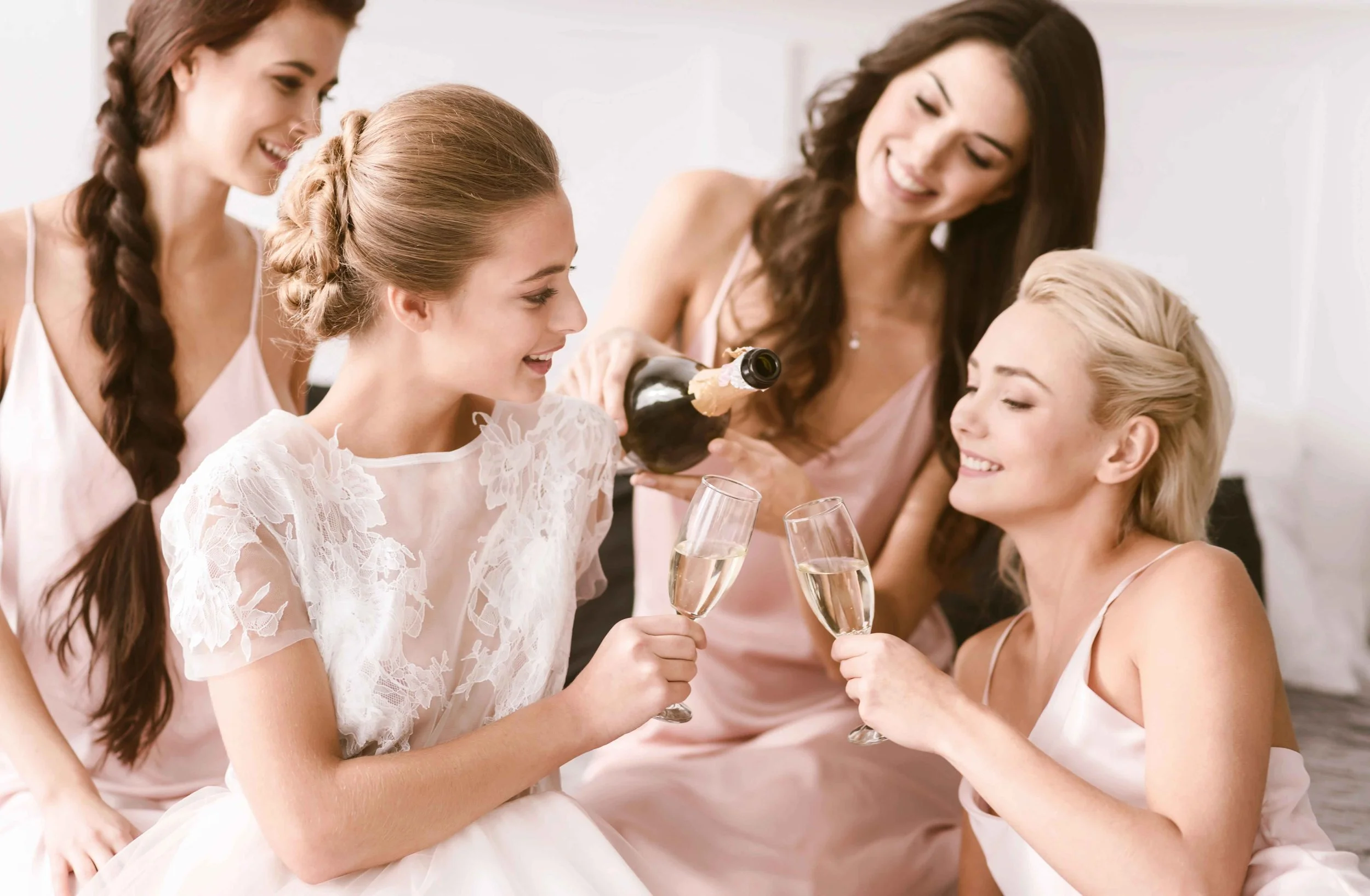 Bride and her friends celebrating with sparking wines in hands.