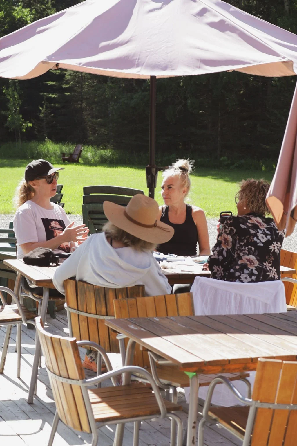 A group of women sitting outside at a table chatting over lunch at a yoga retreat.