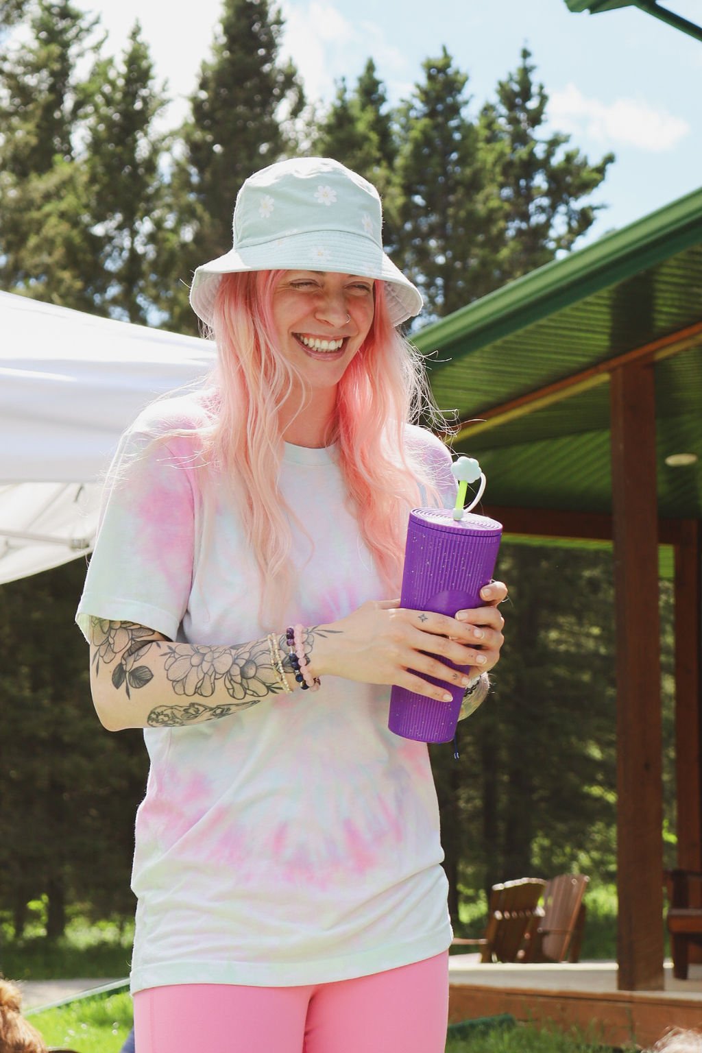 Woman standing outside on a beautiful day, smiling and holding a purple water bottle.