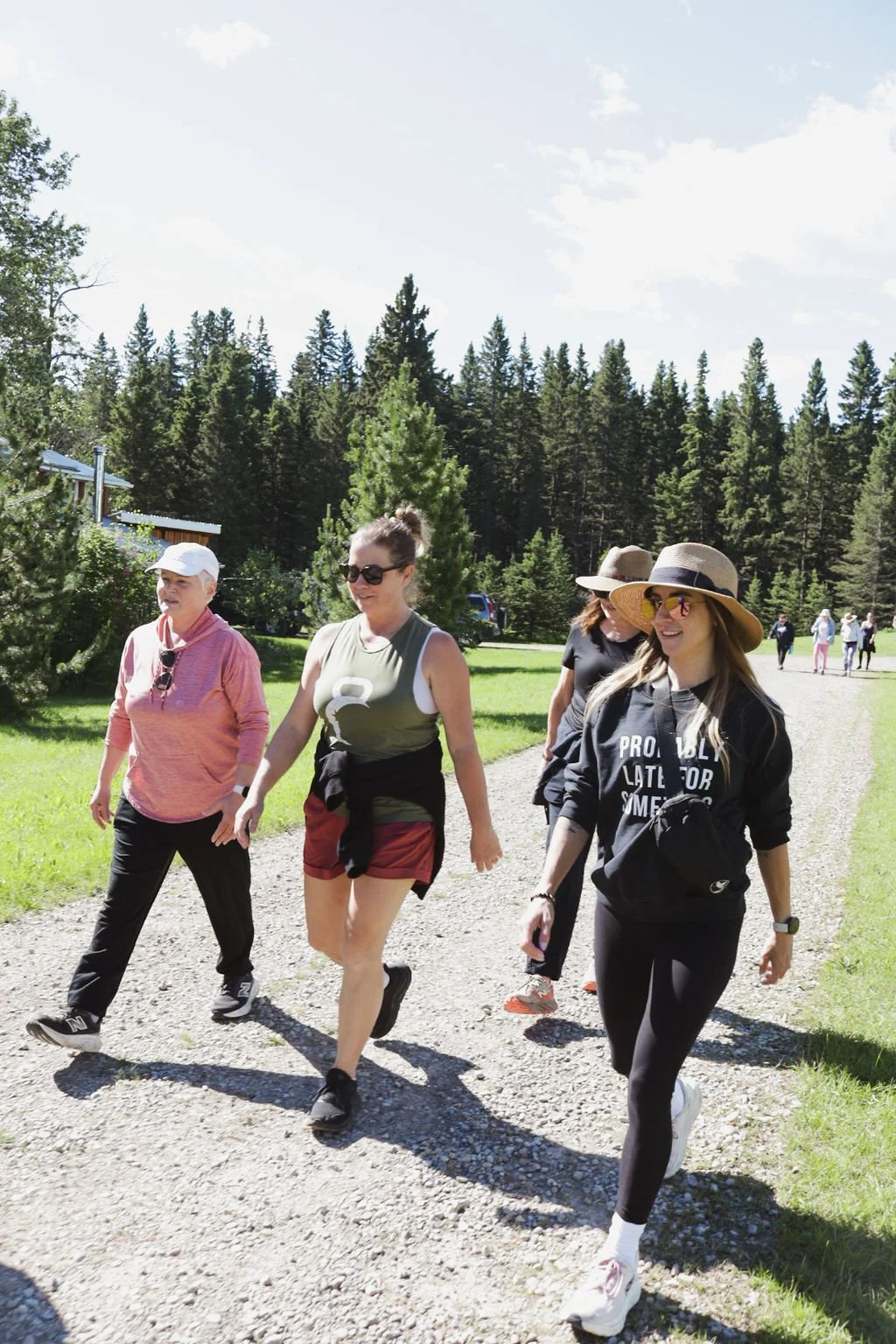 A group of people outside going for a walk through the trees wearing heats and sunglasses.