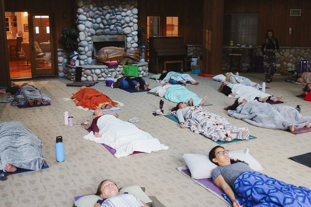 A group lying on the floor in cozy blankets doing Yoga Nidra at a Yoga Retreat in Alberta.