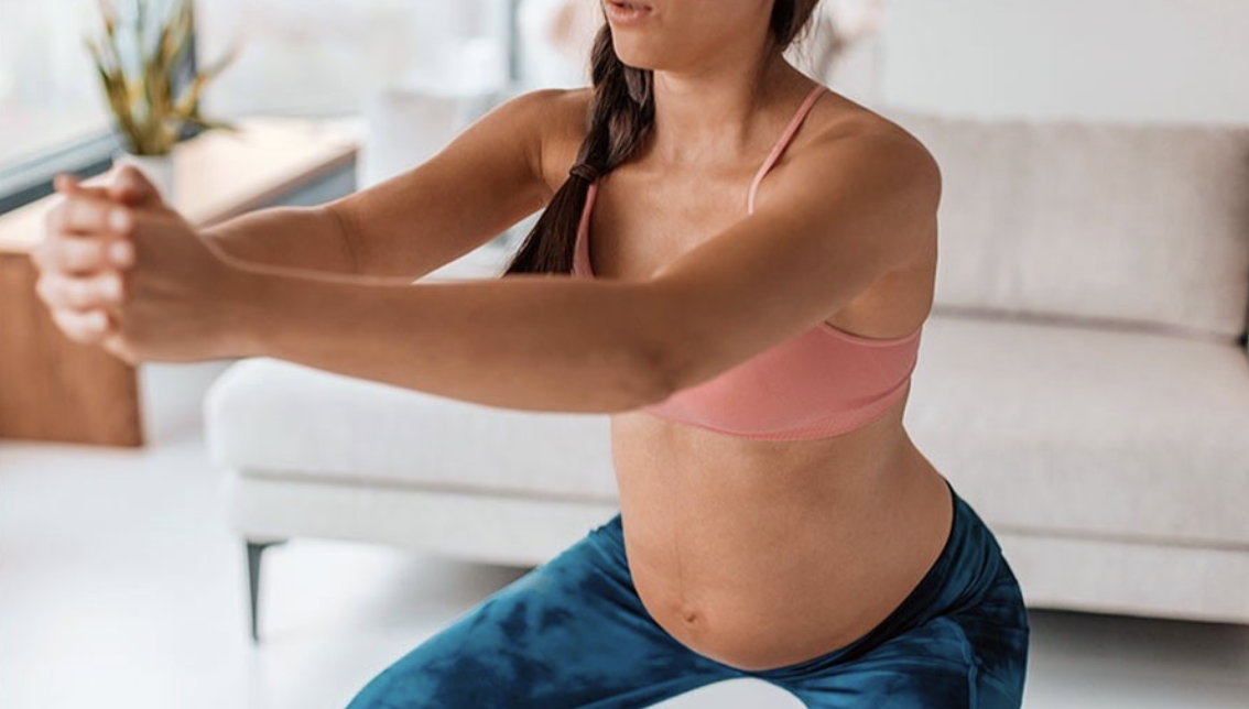 Pregnant woman does a squat during a workout