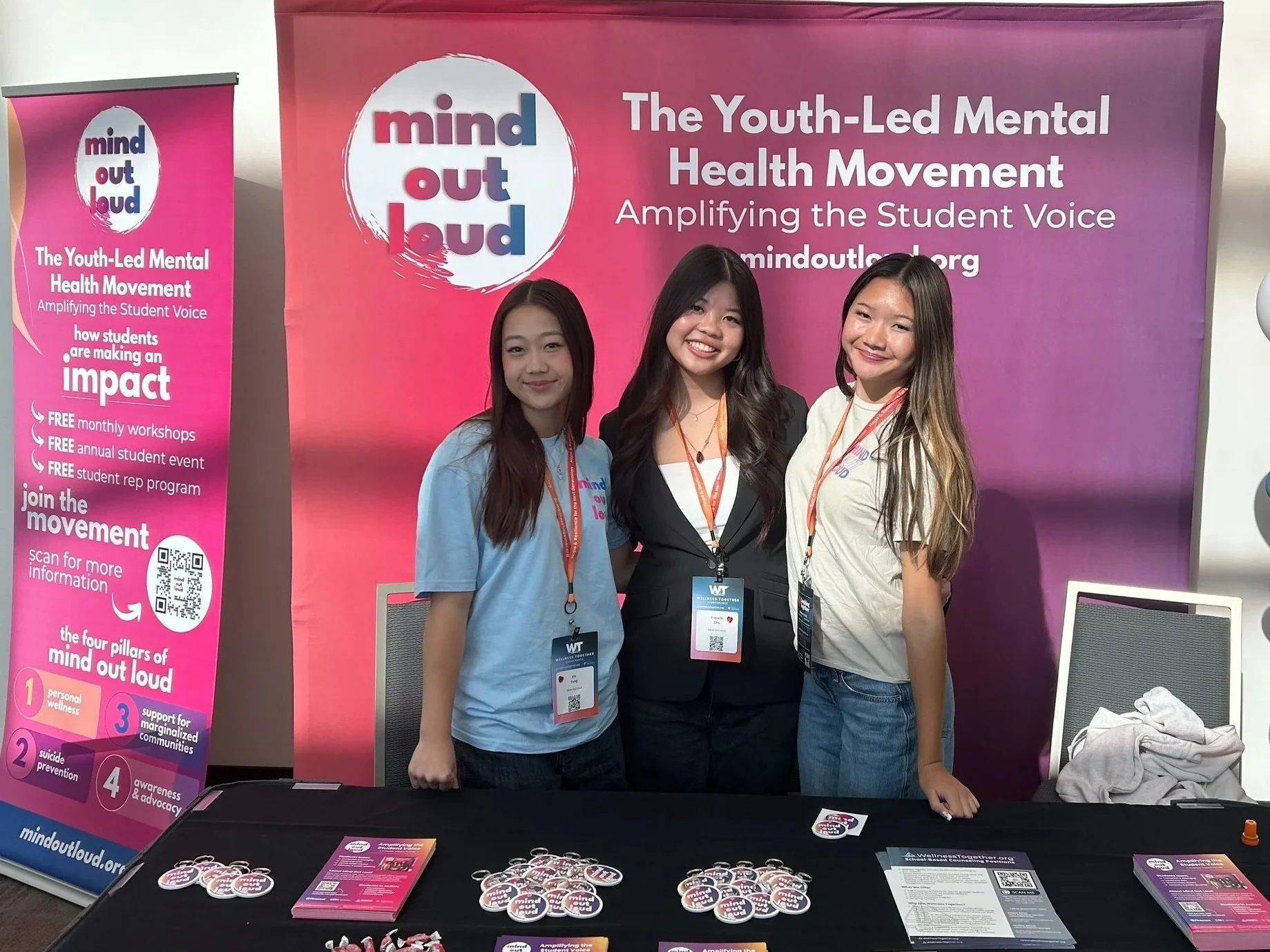 Two people smiling at a craft fair with teddy bears in the background.