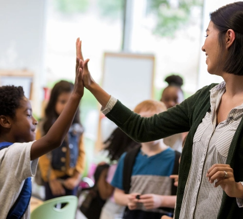 Teacher and student high-fiving in a classroom
