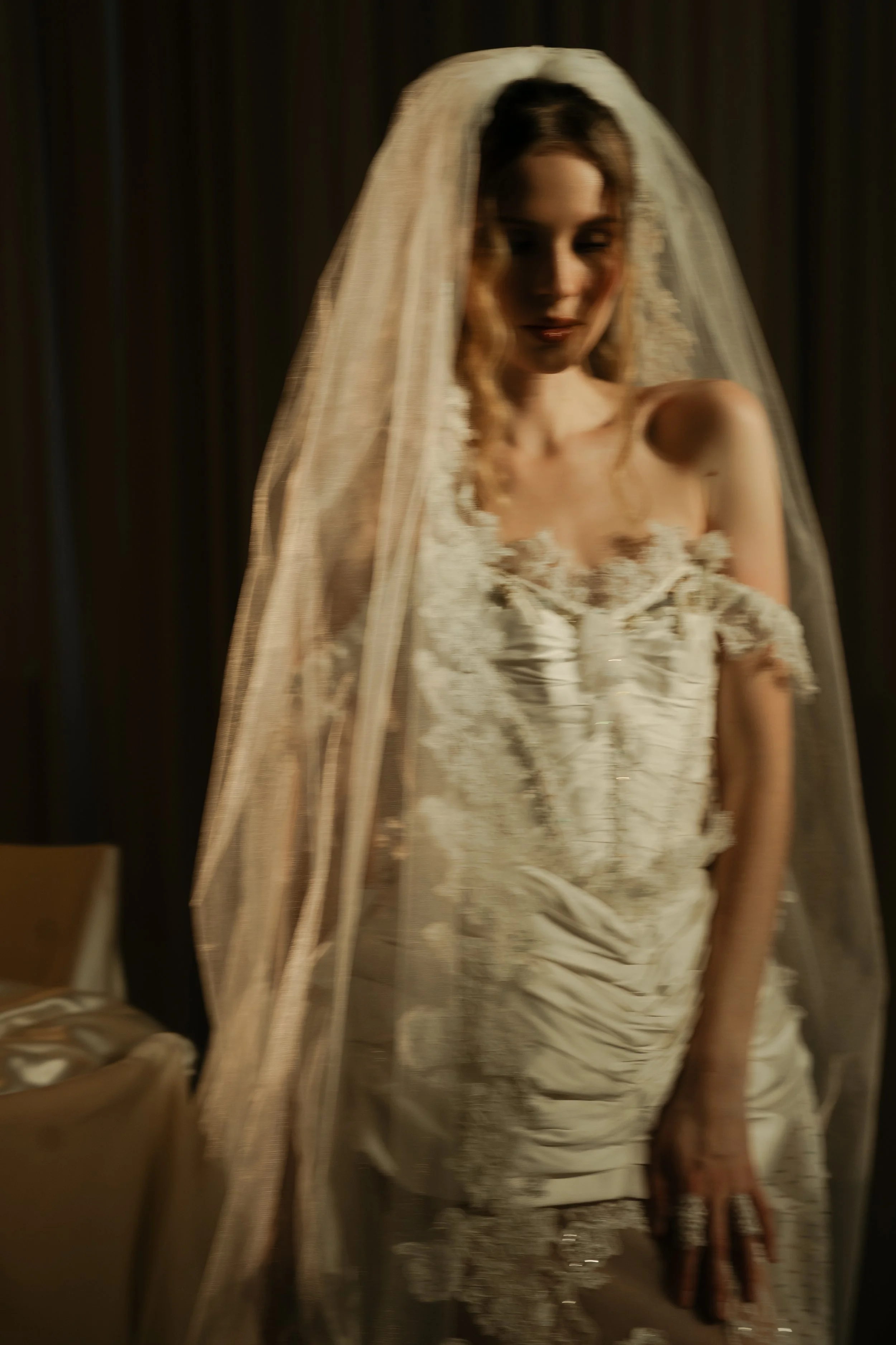 A woman in a wedding dress with a lace veil, posing in front of a mirror in a dimly lit room. Anna Aleksandrovna Photography