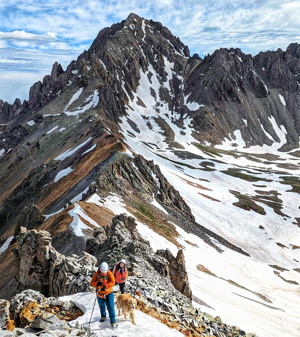 Regina Thomas, Allie Slaten and Harper (doggo) on the North Ridge of Gilpin Peak. Mt. Sneffels (14,155') and its SW Ridge in the background.