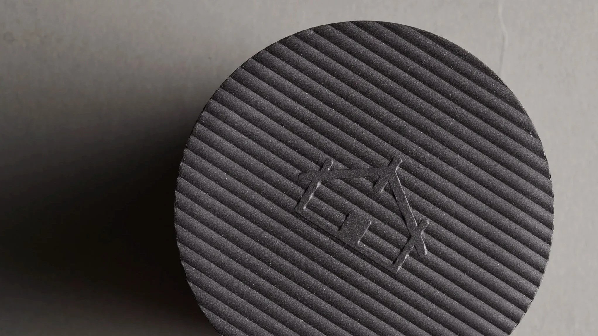 Close-up of a textured black honey jar for tihi manuka honey with the logo embossed on it.