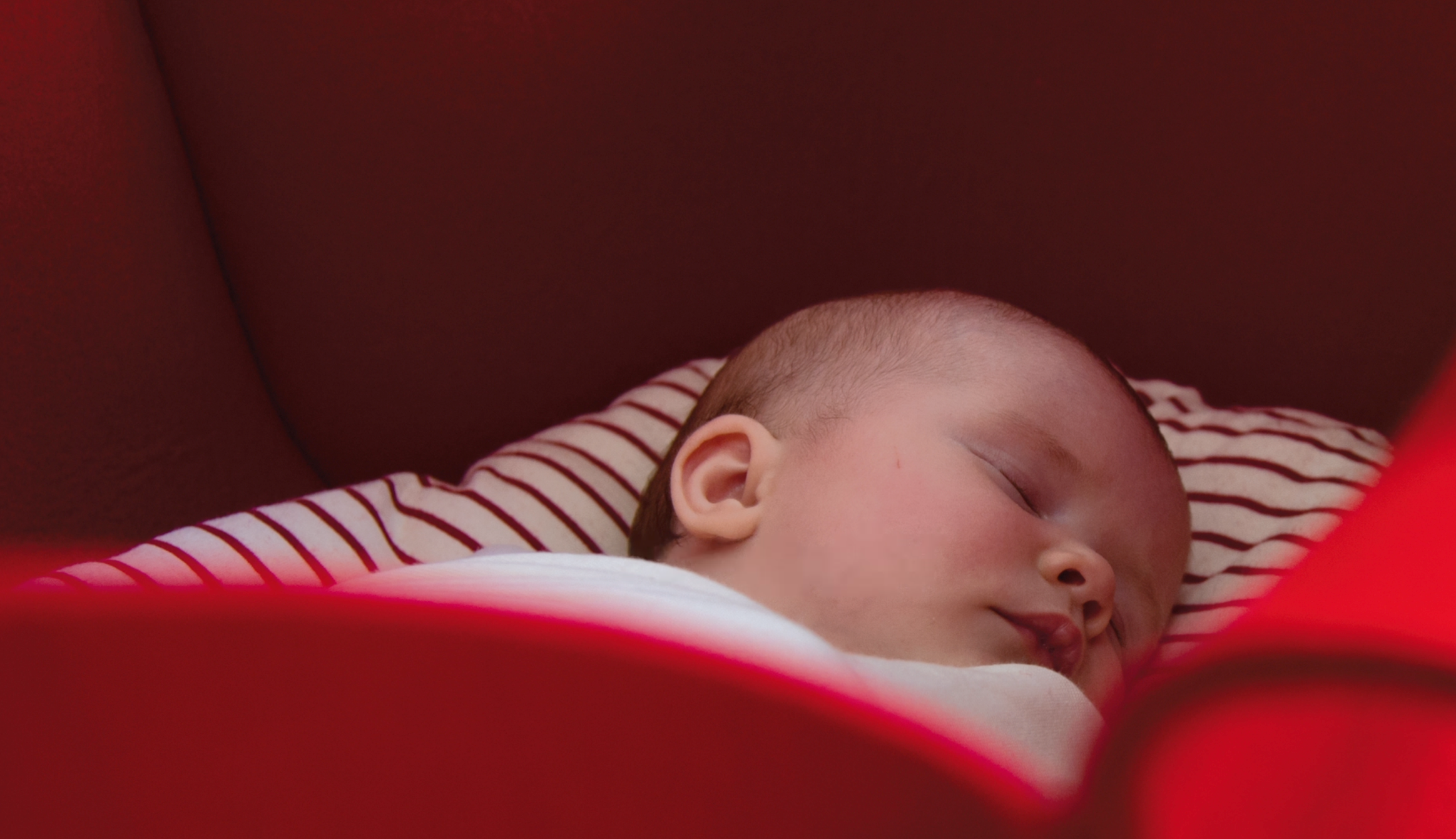 Close-up of a sleeping baby with a striped shirt, resting peacefully.